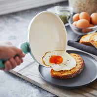 A person sliding a fried egg onto a slice of toast from the Rio Ceramic Nonstick 10" Frypan in the color Turquoise