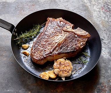 Porterhouse steak being seared in Merten & Storck Carbon Steel frypan