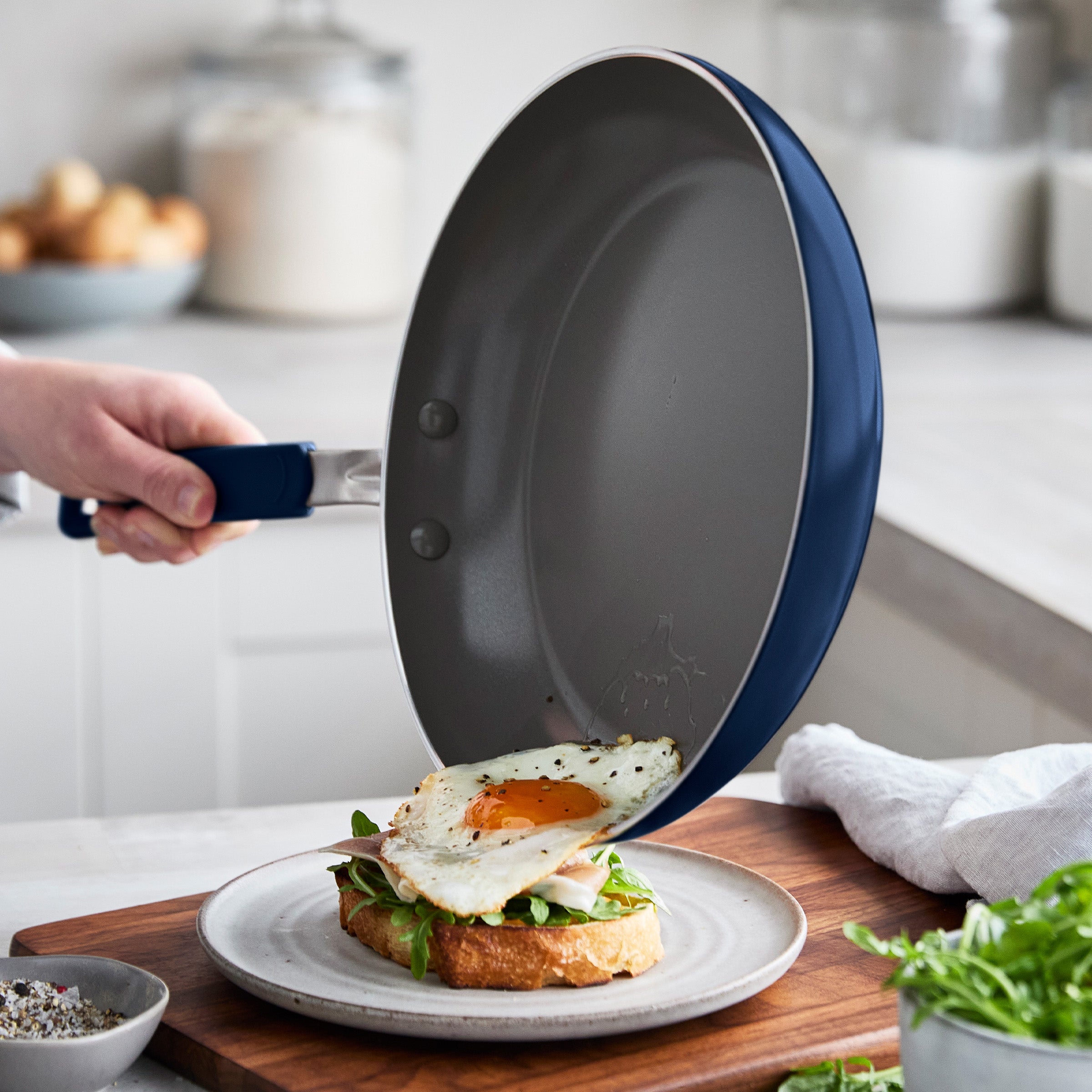 Person sliding an egg from a frypan onto a piece on avocado toast
