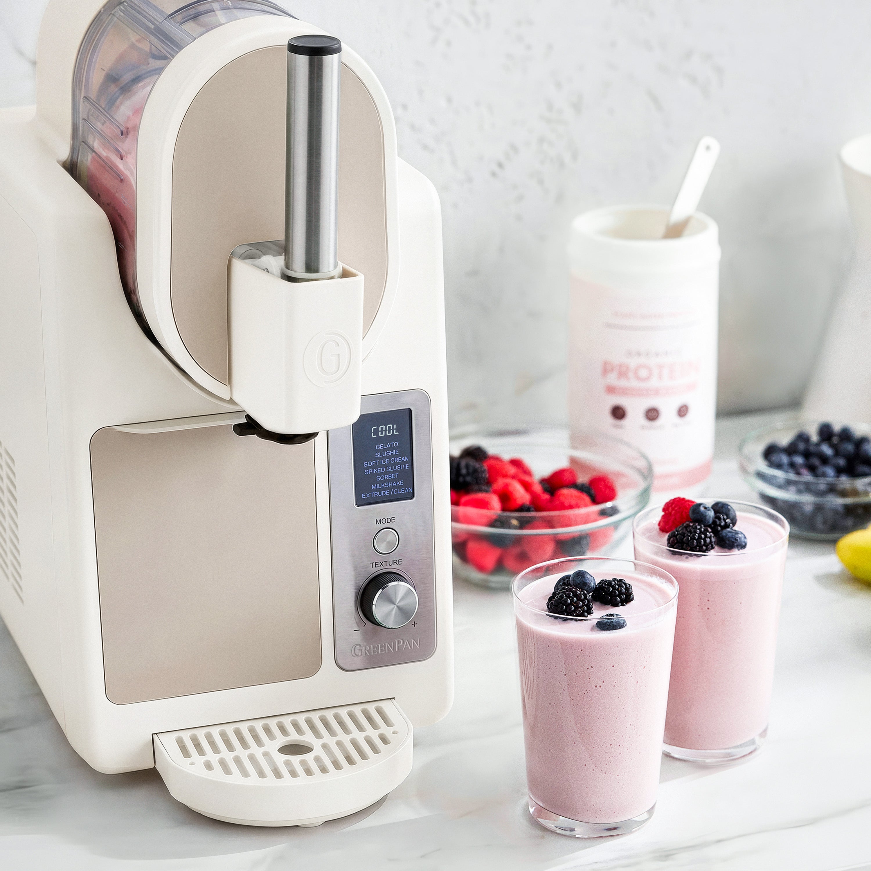 White ice cream maker with smoothies and berries on a marble countertop