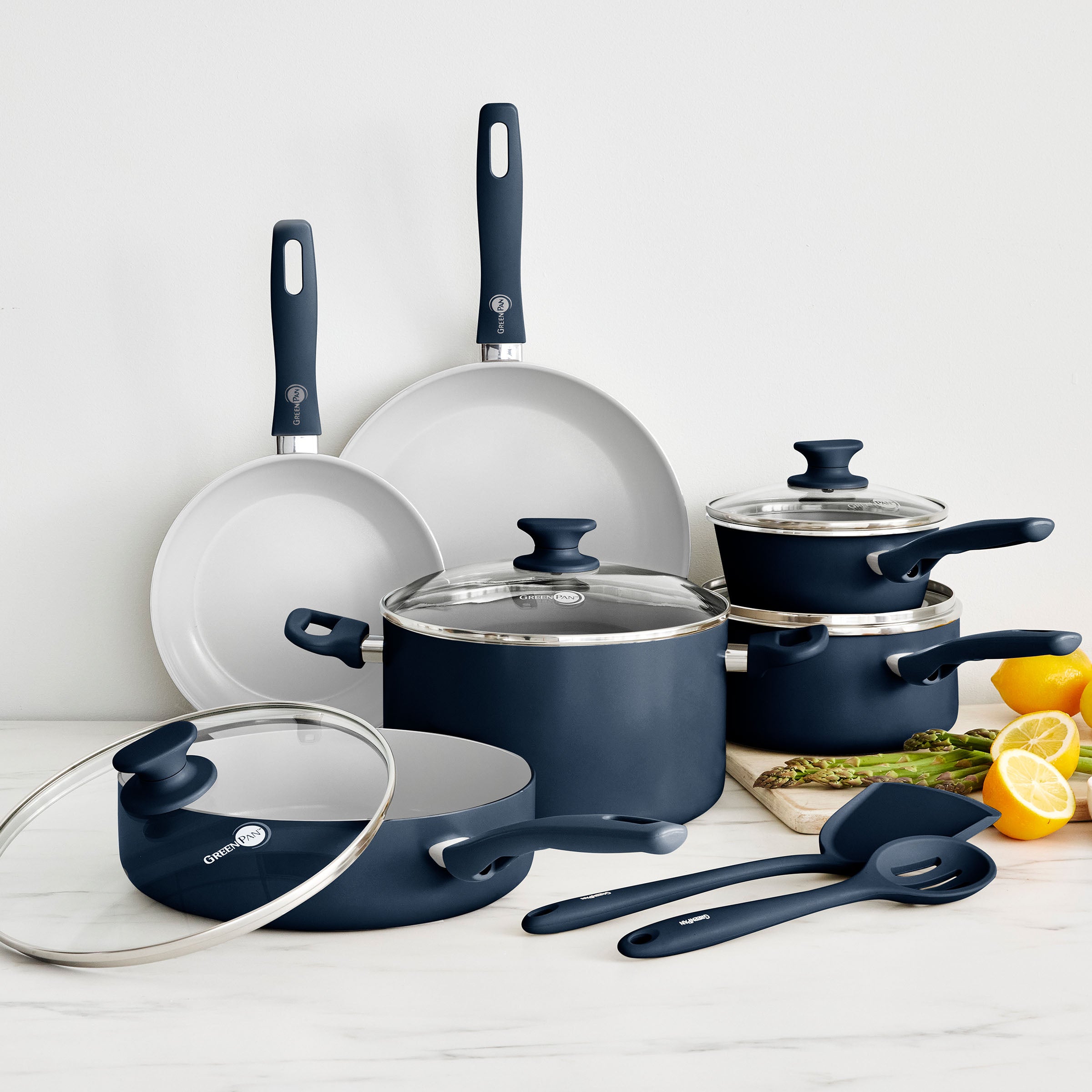 Oxford Blue ceramic nonstick 12-piece cookware set on counter with lemon, orange, and asparagus.