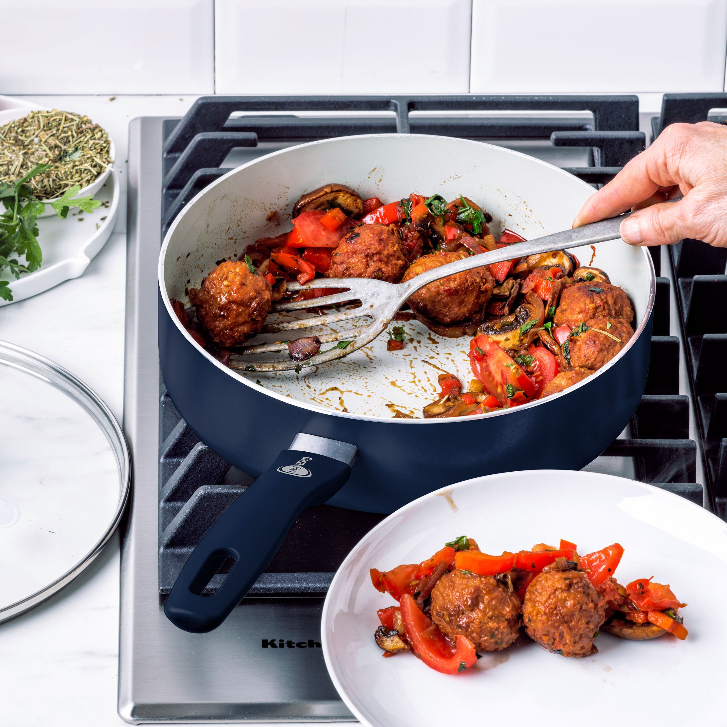 Serving veggie meatballs and vegetables from a blue ceramic nonstick pan onto a plate; part of a 12-piece cookware set.