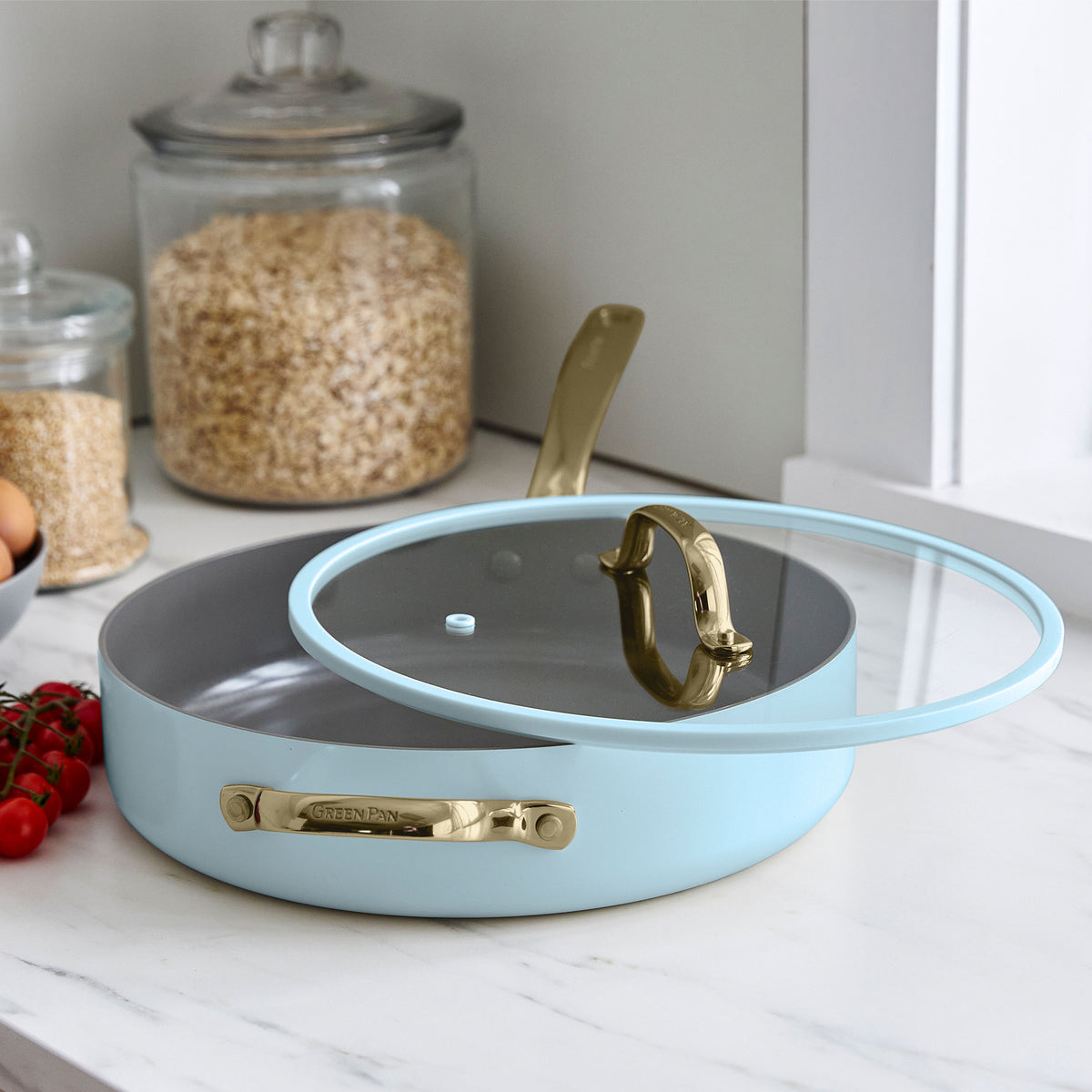 11-piece Glacier blue ceramic cookware set on a white counter with oats and tomatoes nearby.