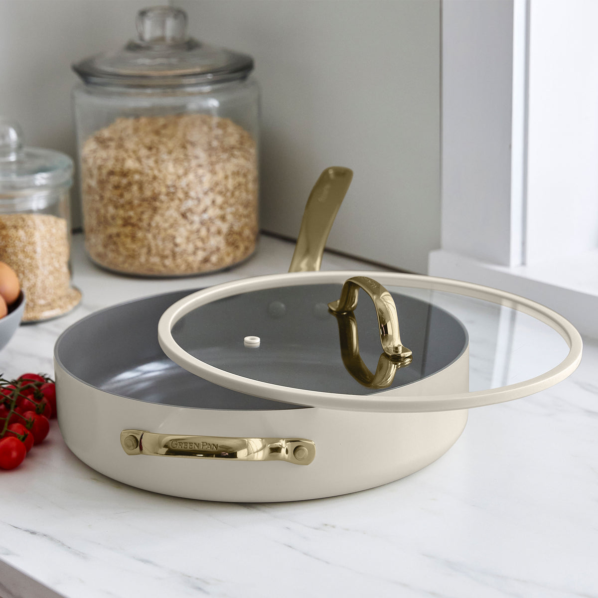 Taupe ceramic nonstick 11-piece cookware set on a white counter with oats, eggs, and tomatoes nearby.