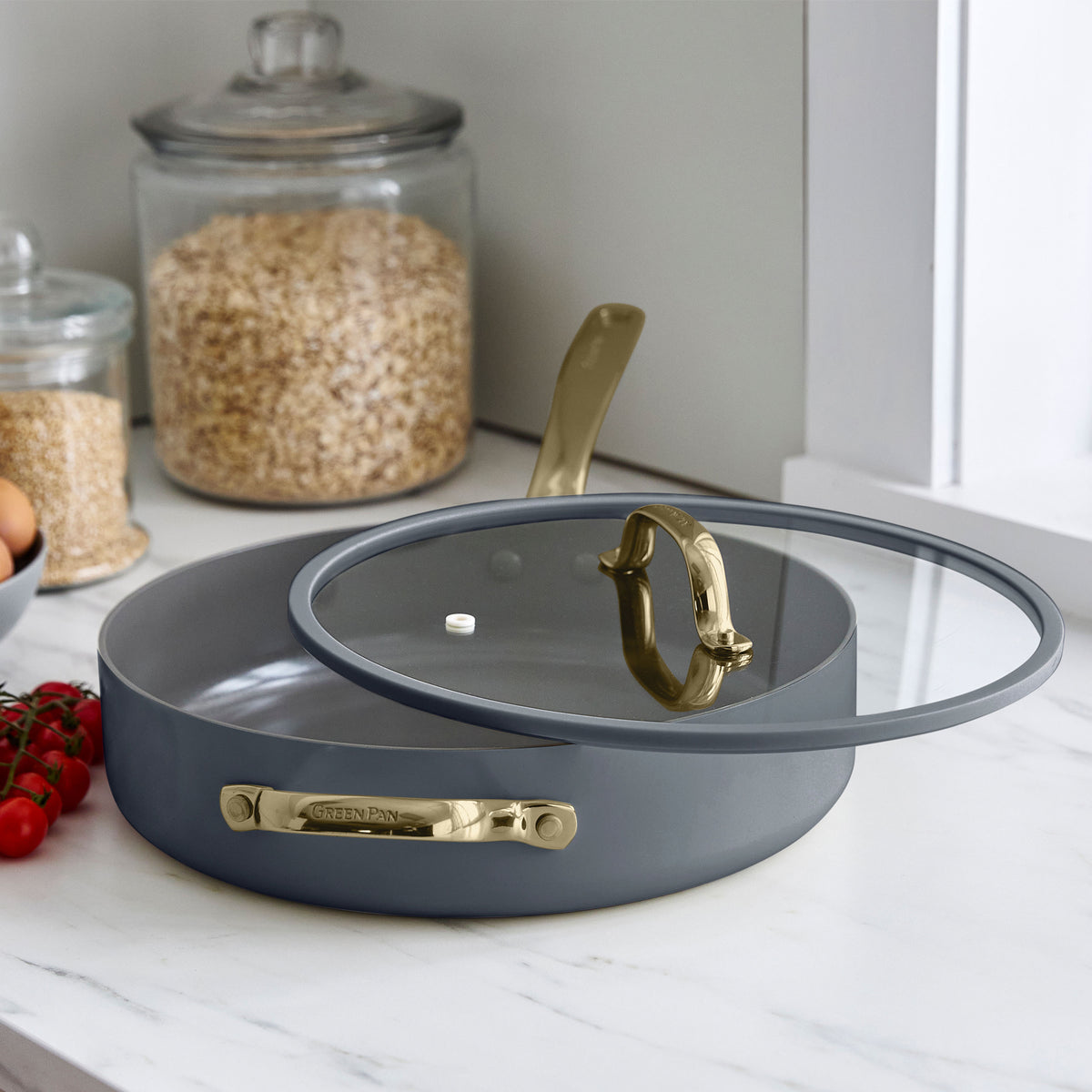 Slate ceramic nonstick cookware set with gold handles and lids, 11 pieces, displayed on marble near oats and tomatoes.