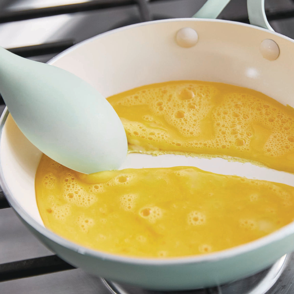 Eggs in a green frypan on a stove