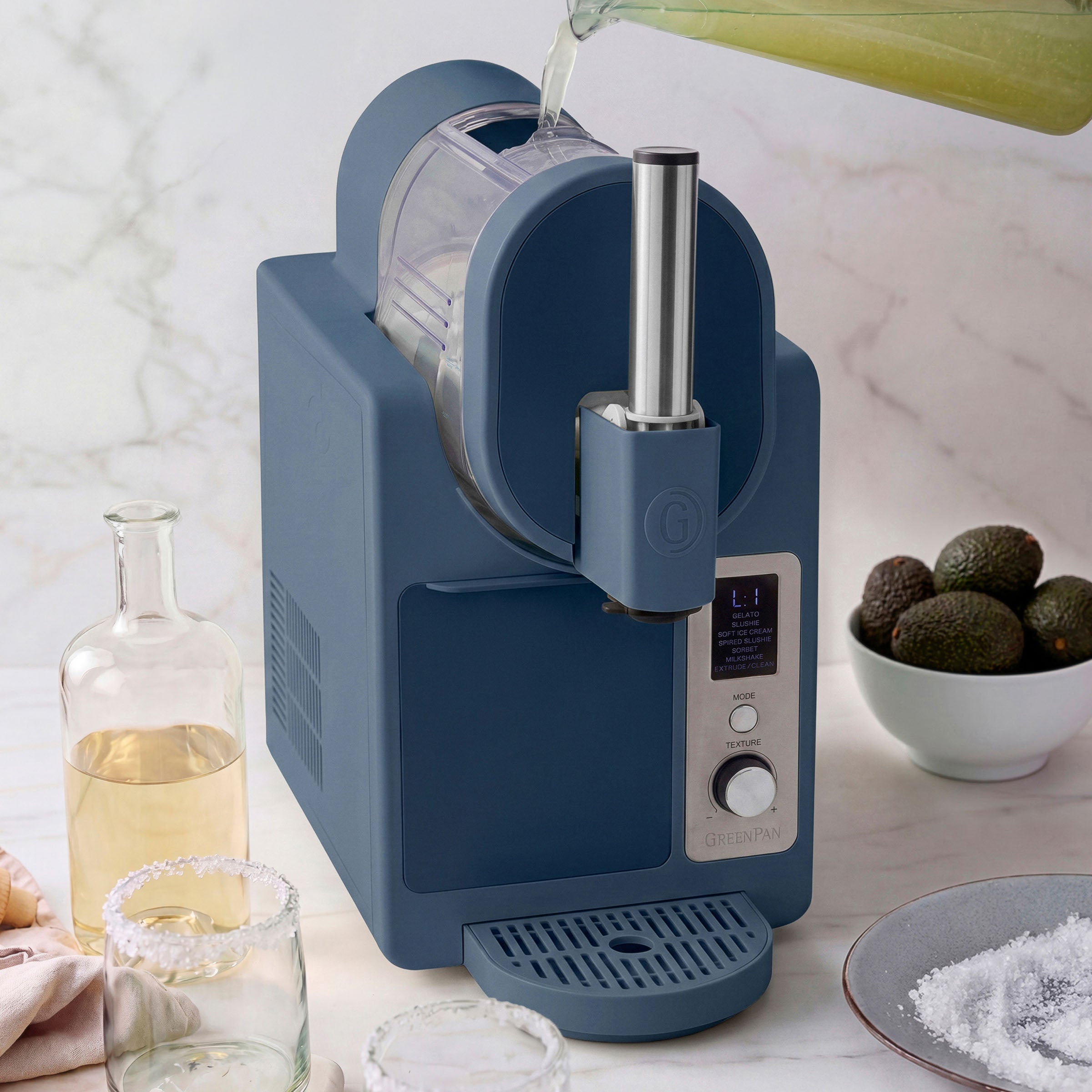 Blue ice cream maker with avocados on a marble countertop