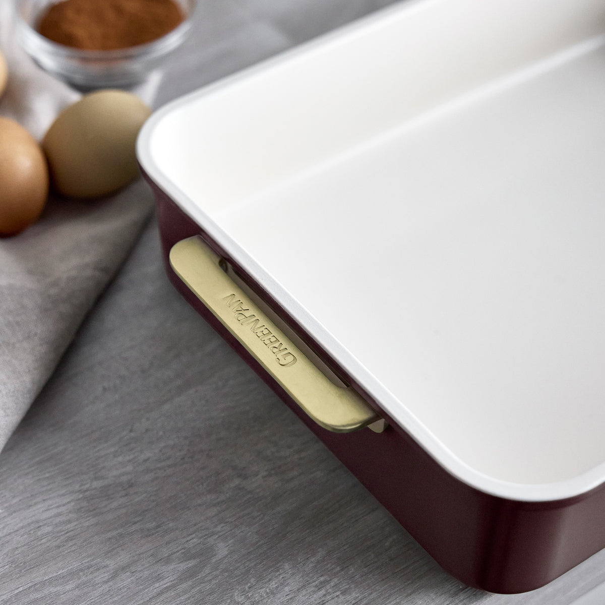 13″ x 9″ rectangular aluminized steel baking pan in Bordeaux with a white interior and gold-toned handles.