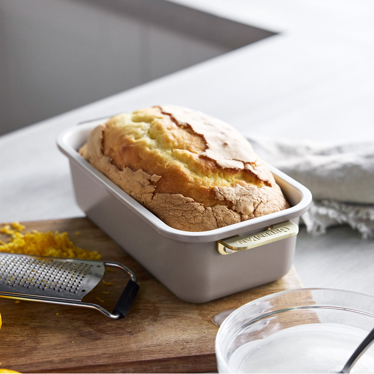 Pound cake in a Latte Reserve Bakeware 7-piece loaf pan with gold-tone handles on a wooden cutting board.