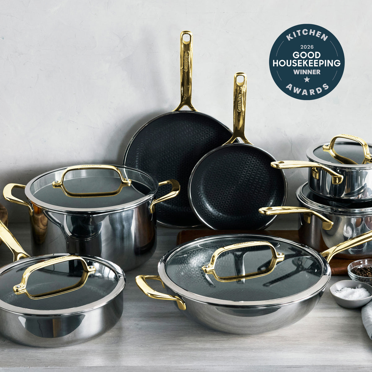 12-piece cookware set with stainless steel pots, white ceramic nonstick pans, and gold handles.