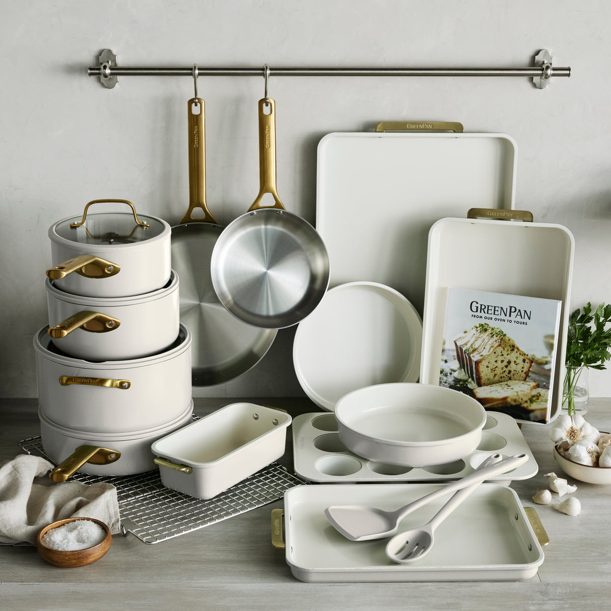 White kitchenware set with gold handles on a wooden surface.