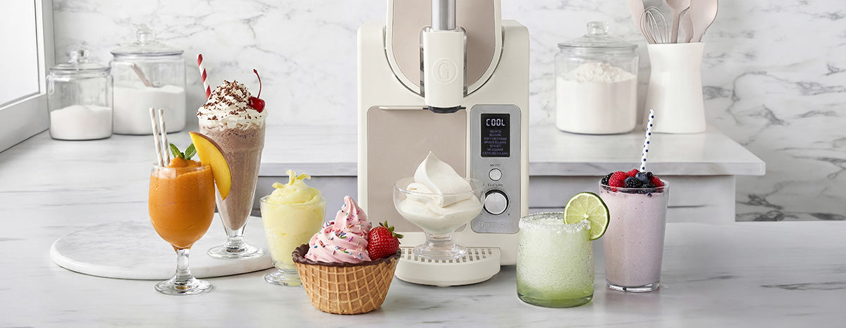 Assorted desserts and drinks on a marble countertop with a Frost Pro kitchen appliance in the background.