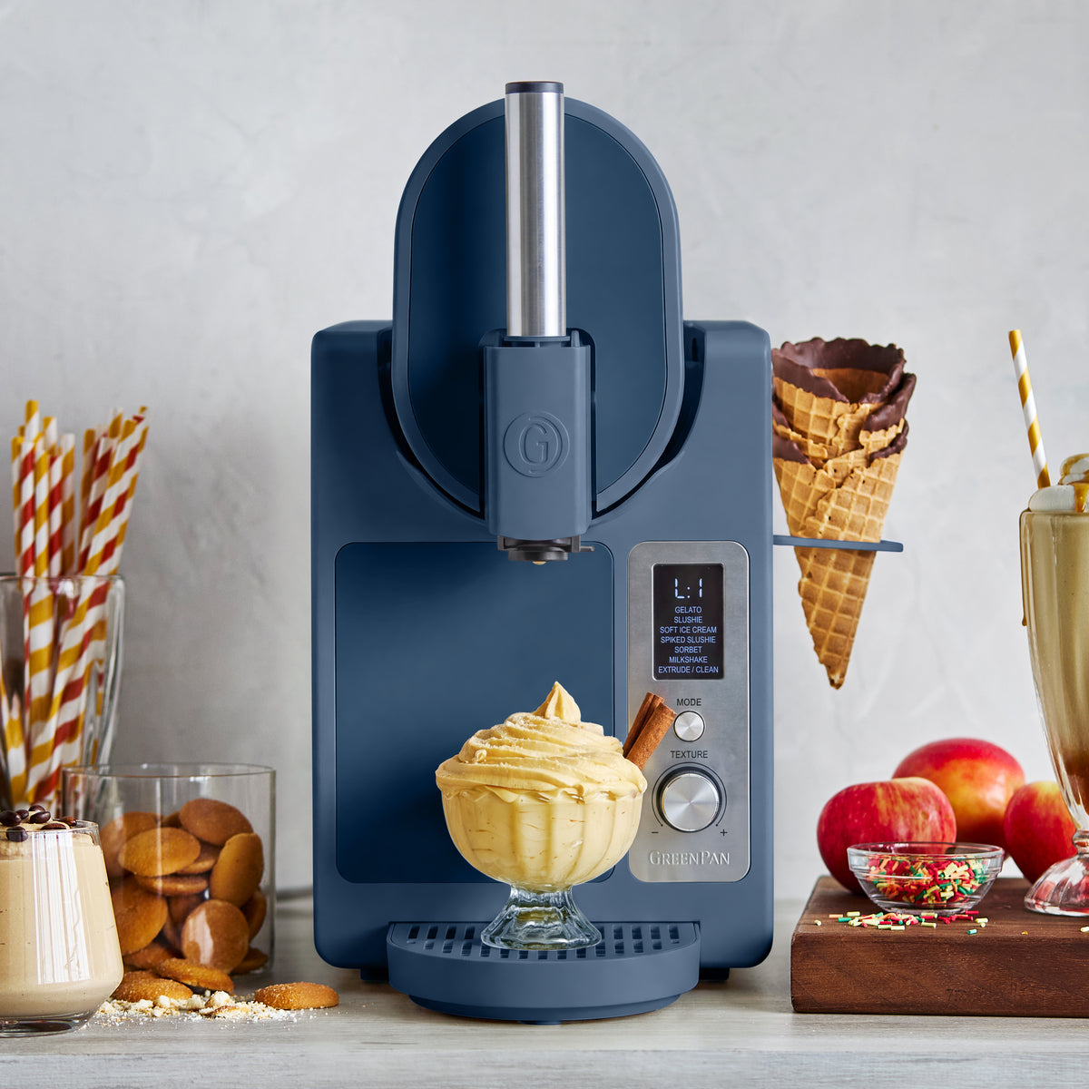 Berry-colored ice cream maker dispensing soft serve into a bowl, with cones and treats arranged on the counter.
