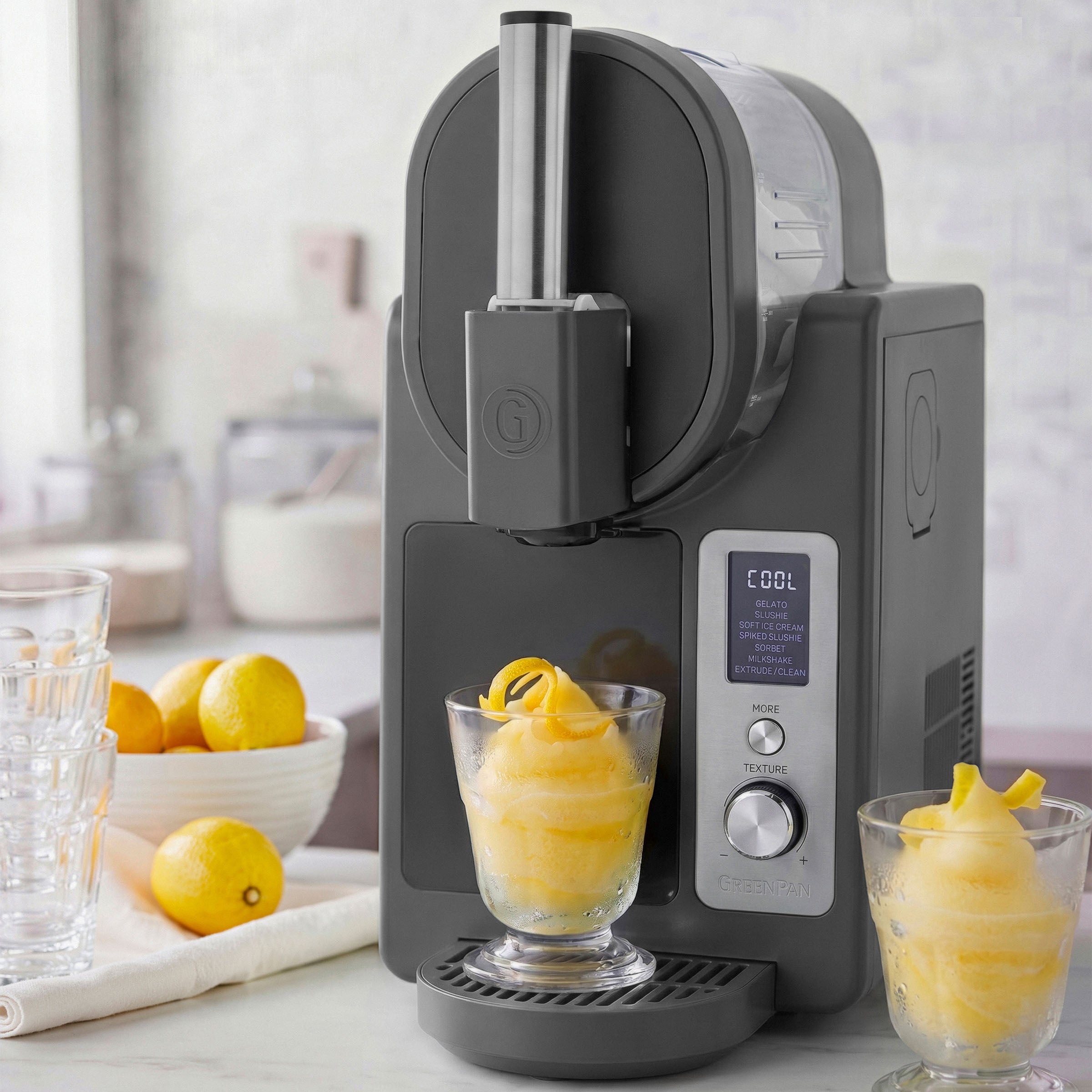 Black ice cream maker with two glasses of lemon sorbet on a kitchen counter.