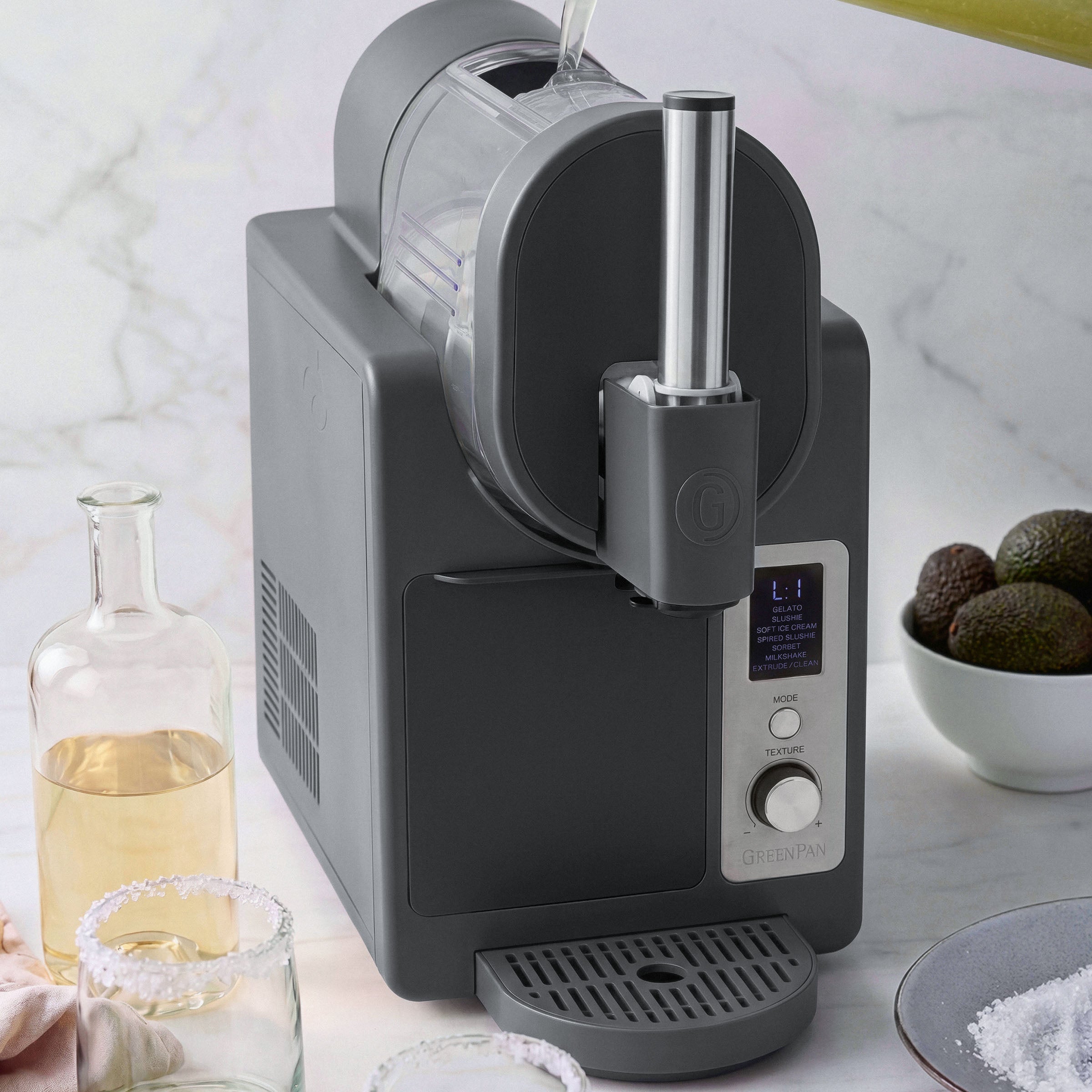 Black ice cream maker with avocados on a marble countertop