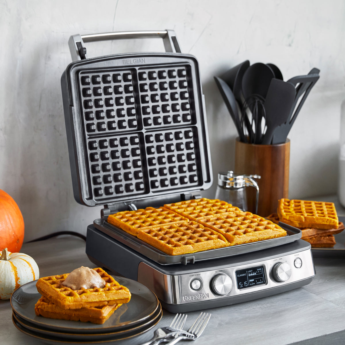 Graphite ceramic waffle maker with four square sections for Belgian waffles.