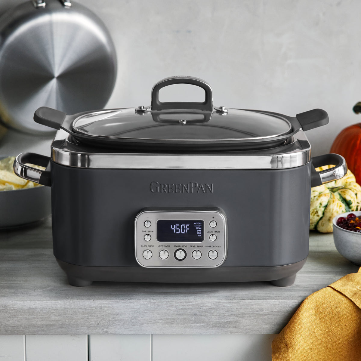 Graphite 14-in-1 slow cooker on a kitchen counter, with food inside and a yellow towel nearby.