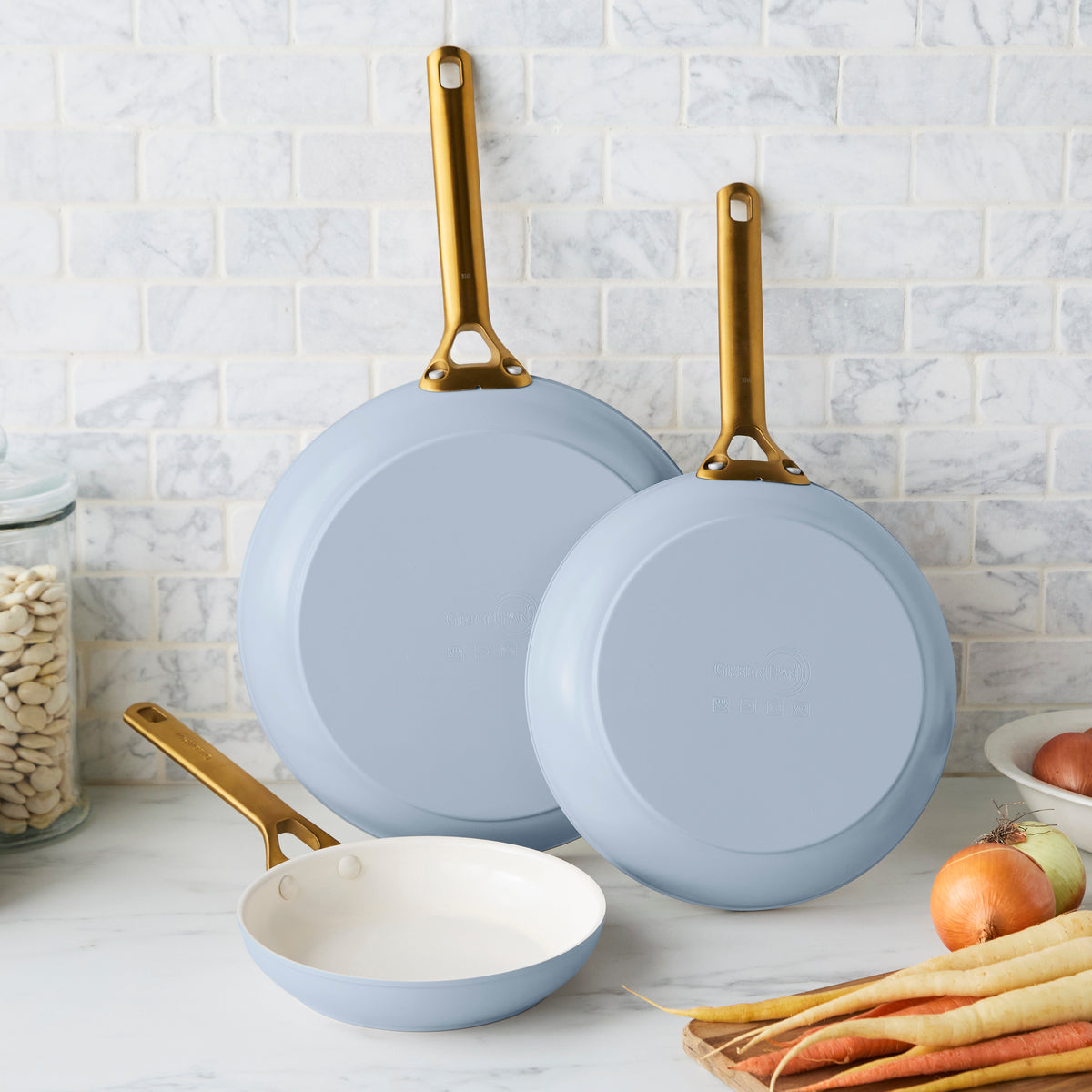 Three blue frypans with gold handles on a kitchen counter