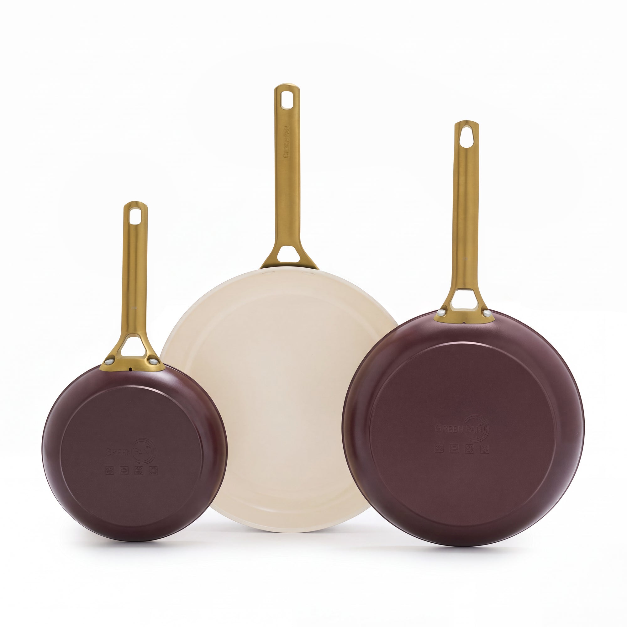 Set of three Bordeaux ceramic nonstick frypans with gold handles, two lying flat and one angled upward on a white background.