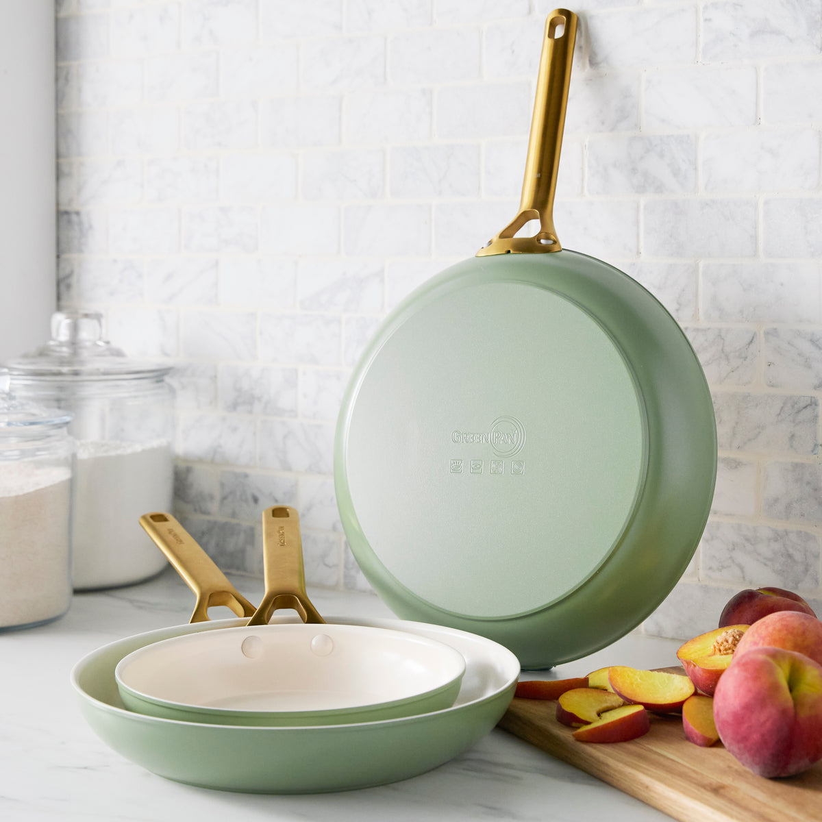 Green frying pans with gold handles on a kitchen counter