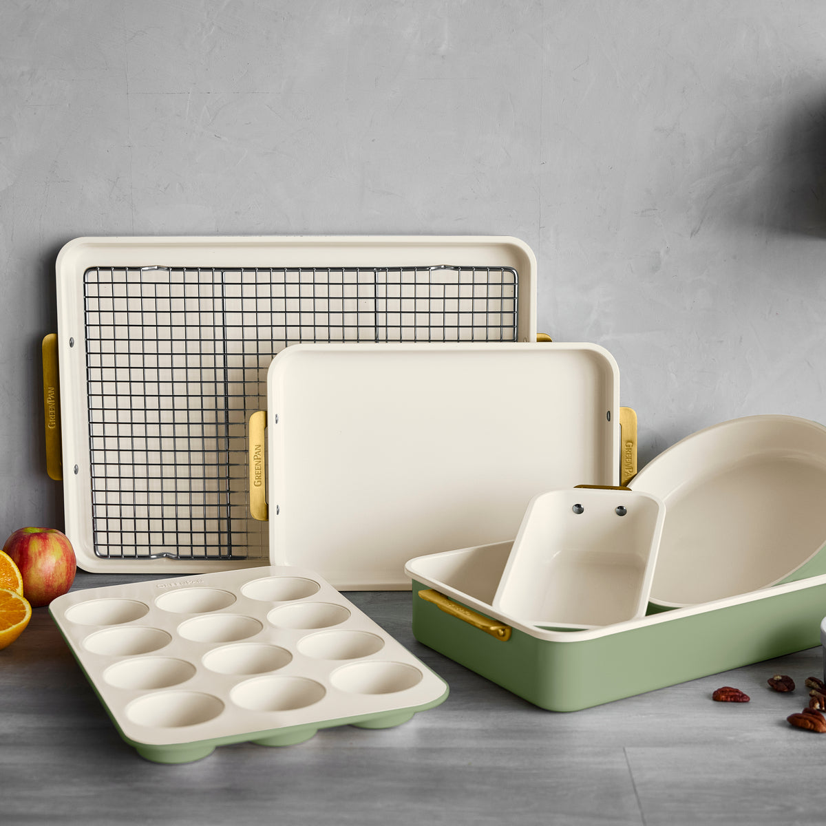 7-piece sage set with cream and green aluminized steel pans, tray, rack, and dish on a gray surface.