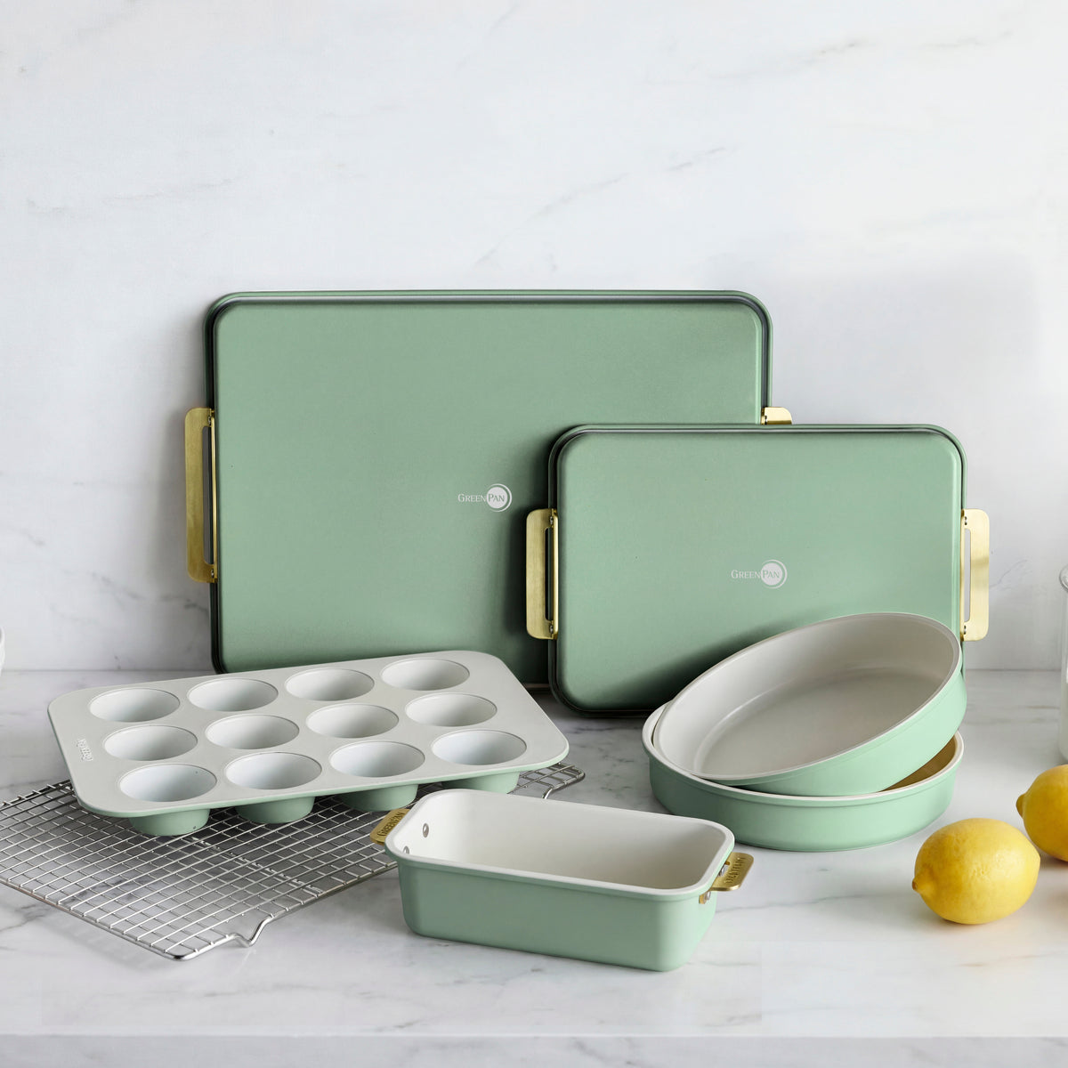 7-piece sage green bakeware set arranged on a kitchen counter with lemons nearby.