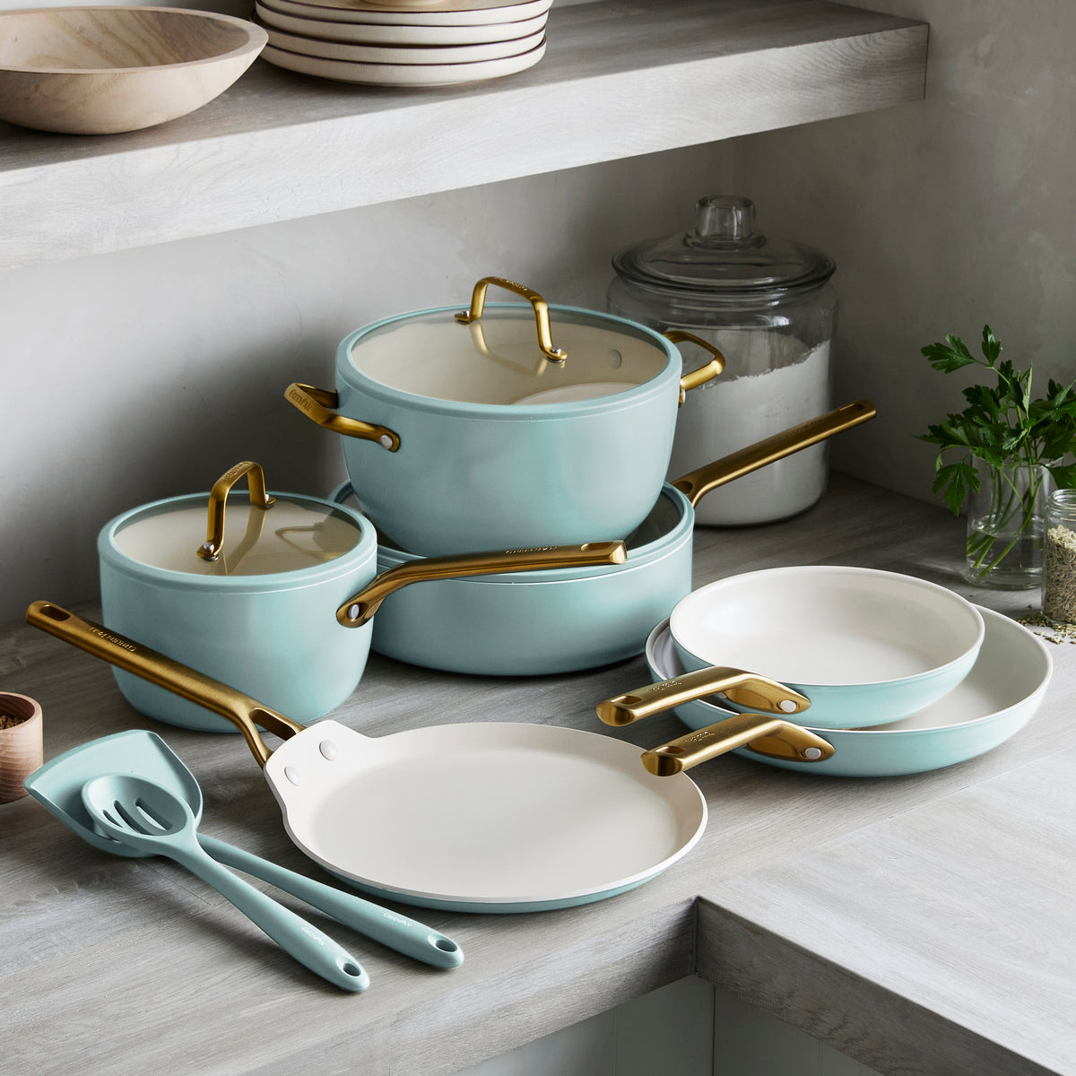Set of light blue cookware with gold handles on a kitchen counter.