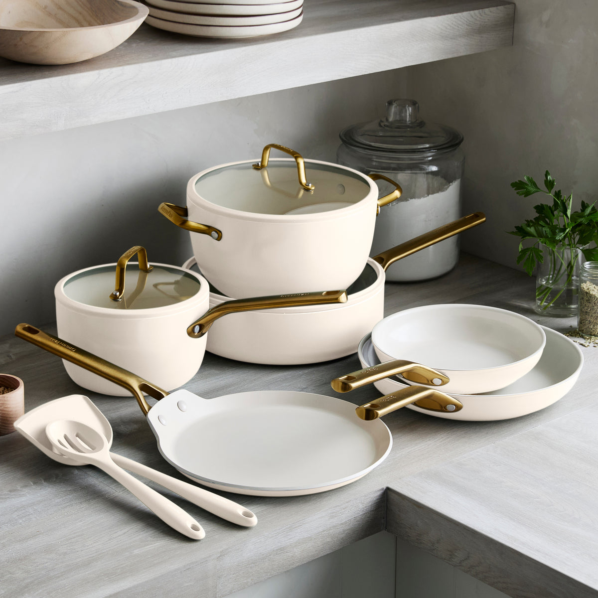 Set of white cookware with gold handles on a kitchen counter.