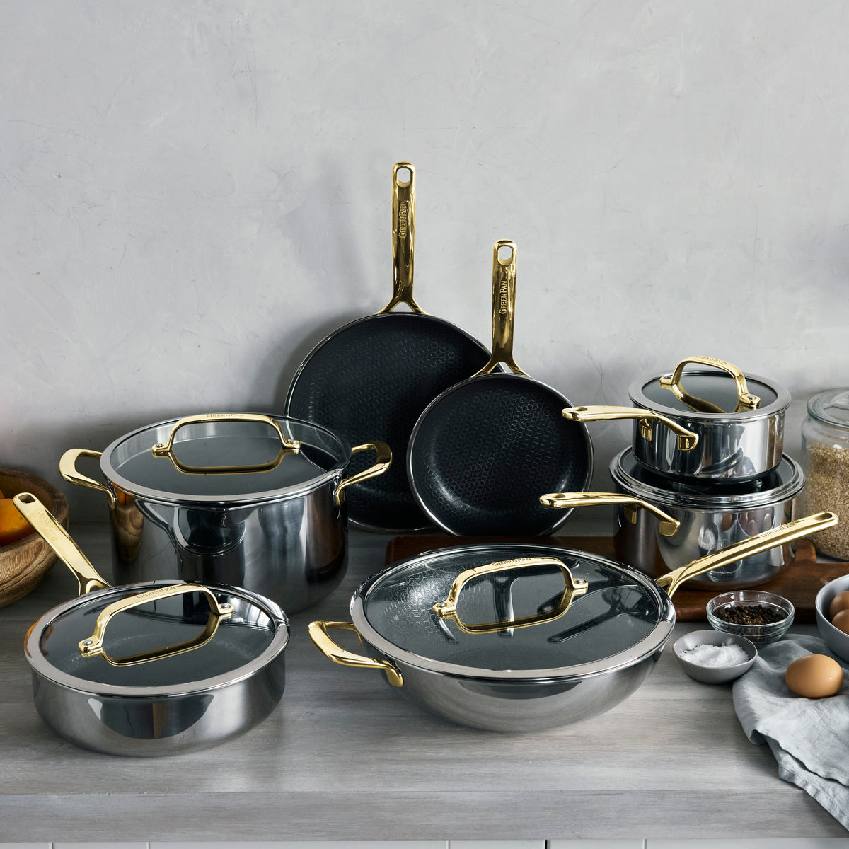 12-piece ceramic nonstick cookware set with gold handles and lids.