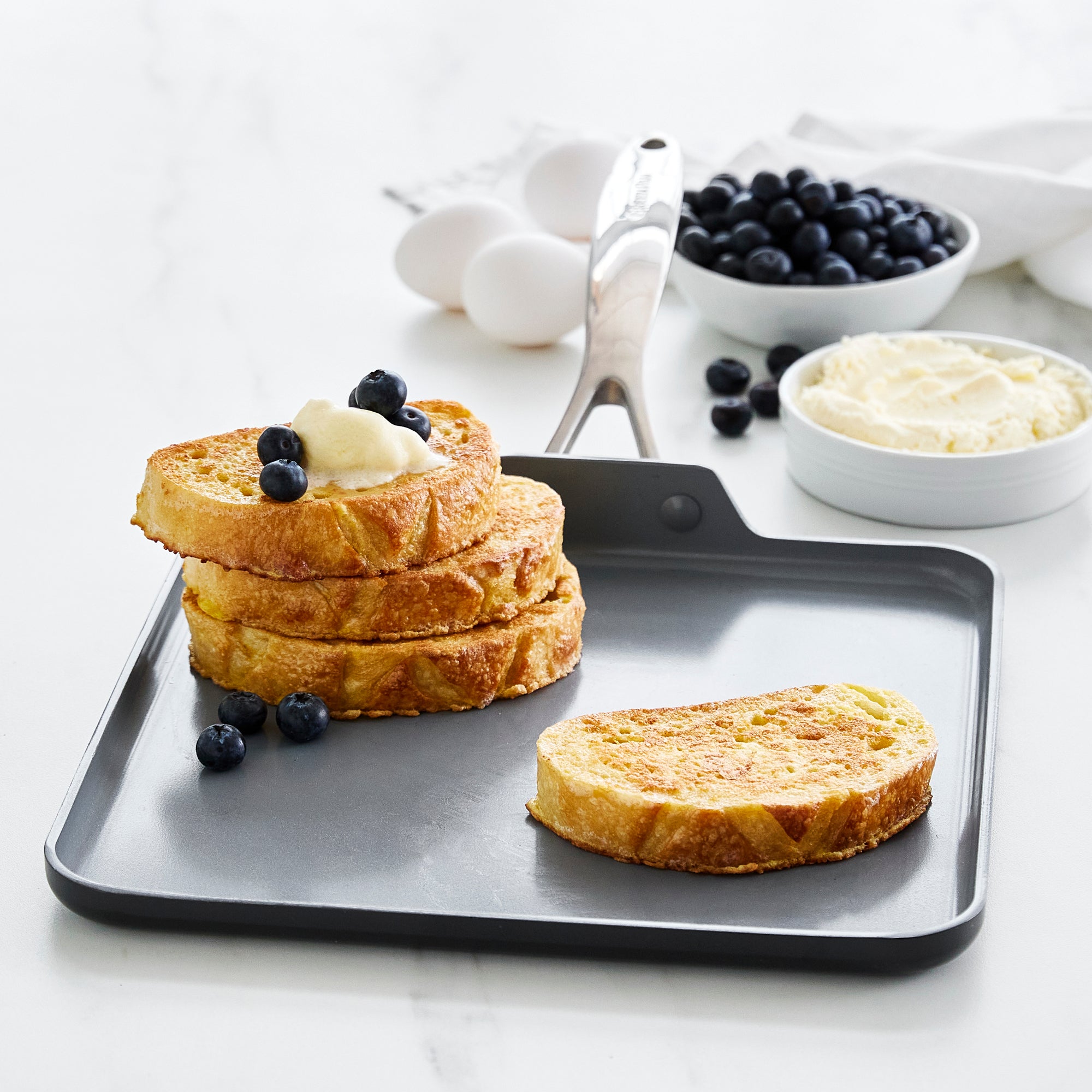French toast with cream and blueberries on a grey ceramic nonstick 11-inch square griddle.
