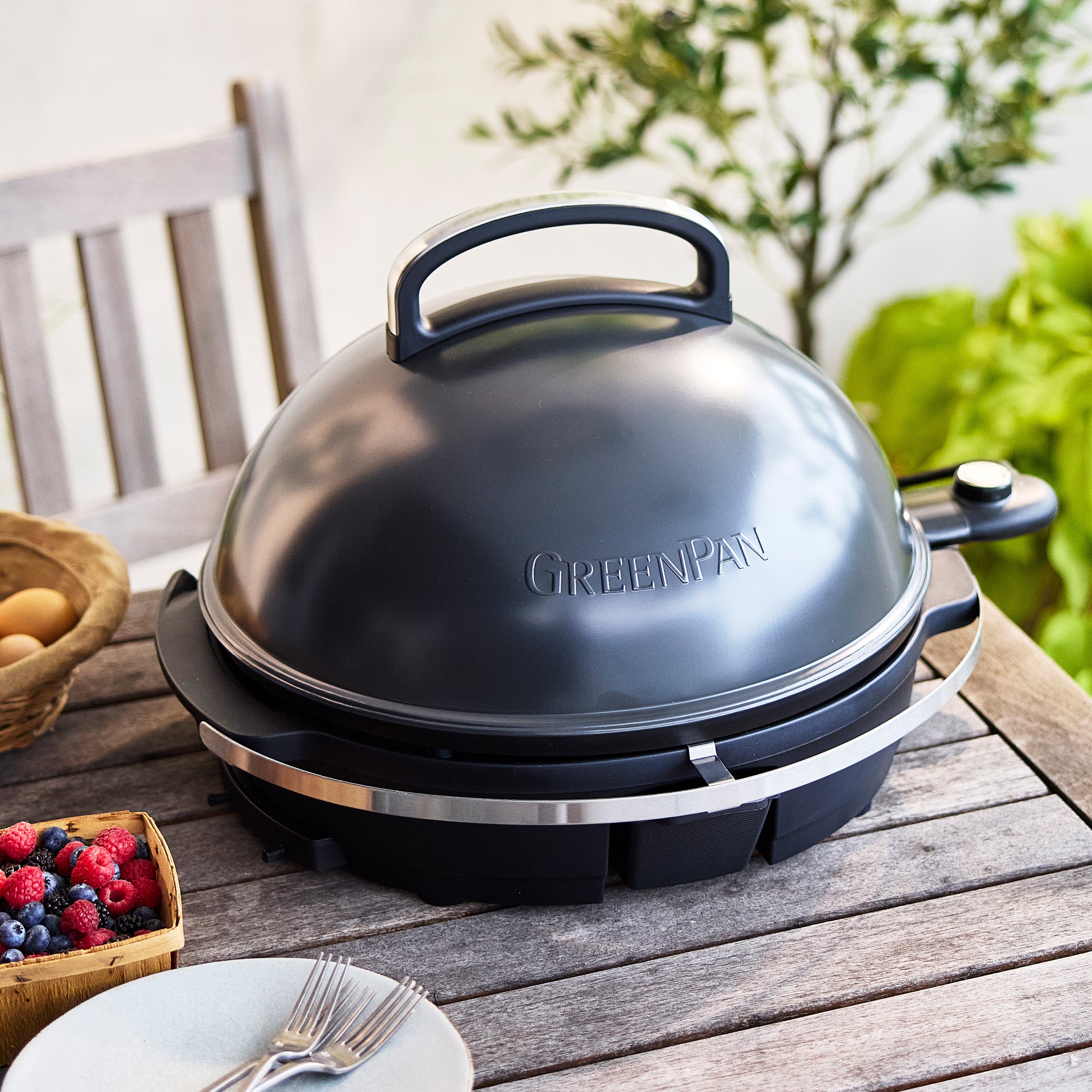 Dark gray portable grill on a wooden table in an outdoor setting