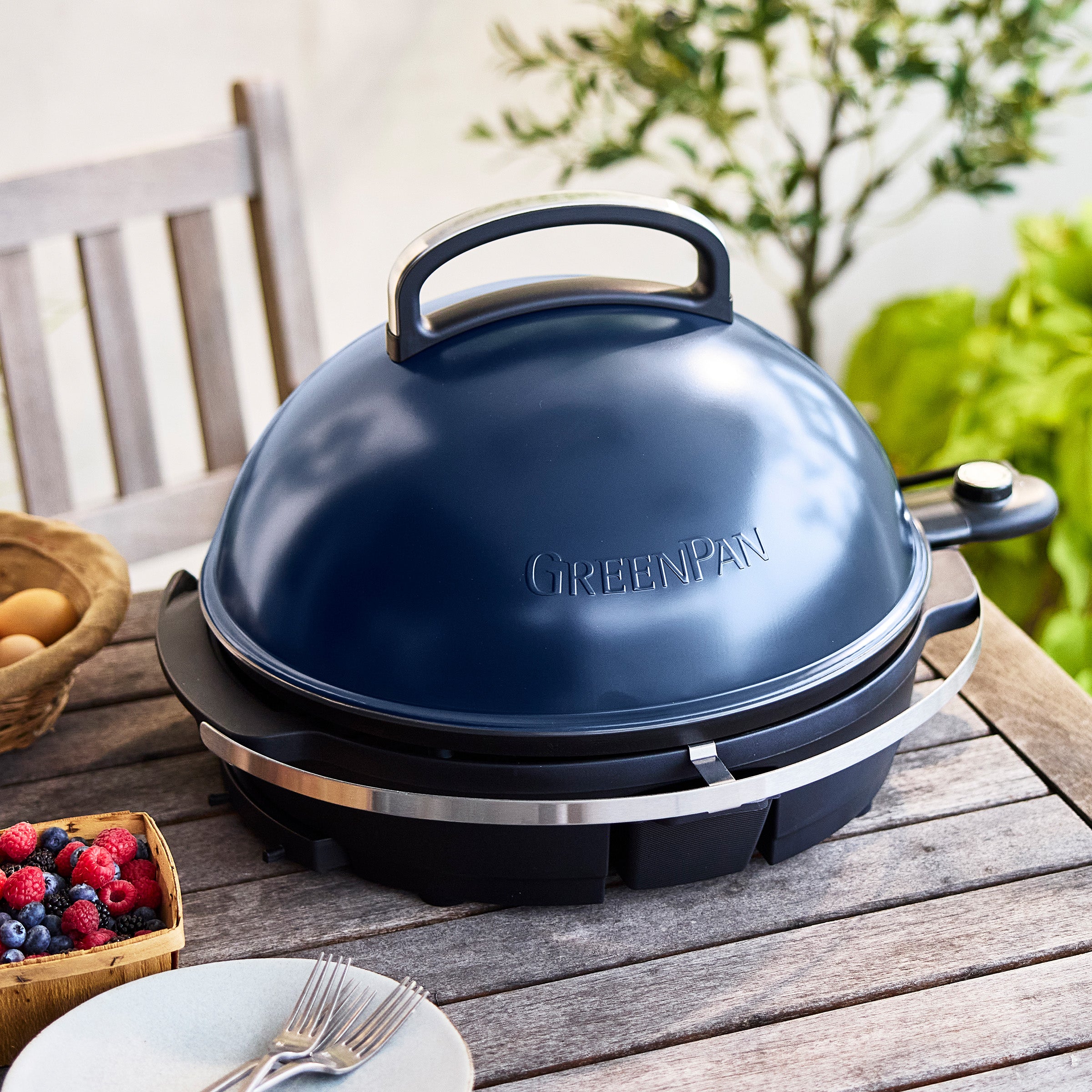 Dark blue portable grill on a wooden table outdoors