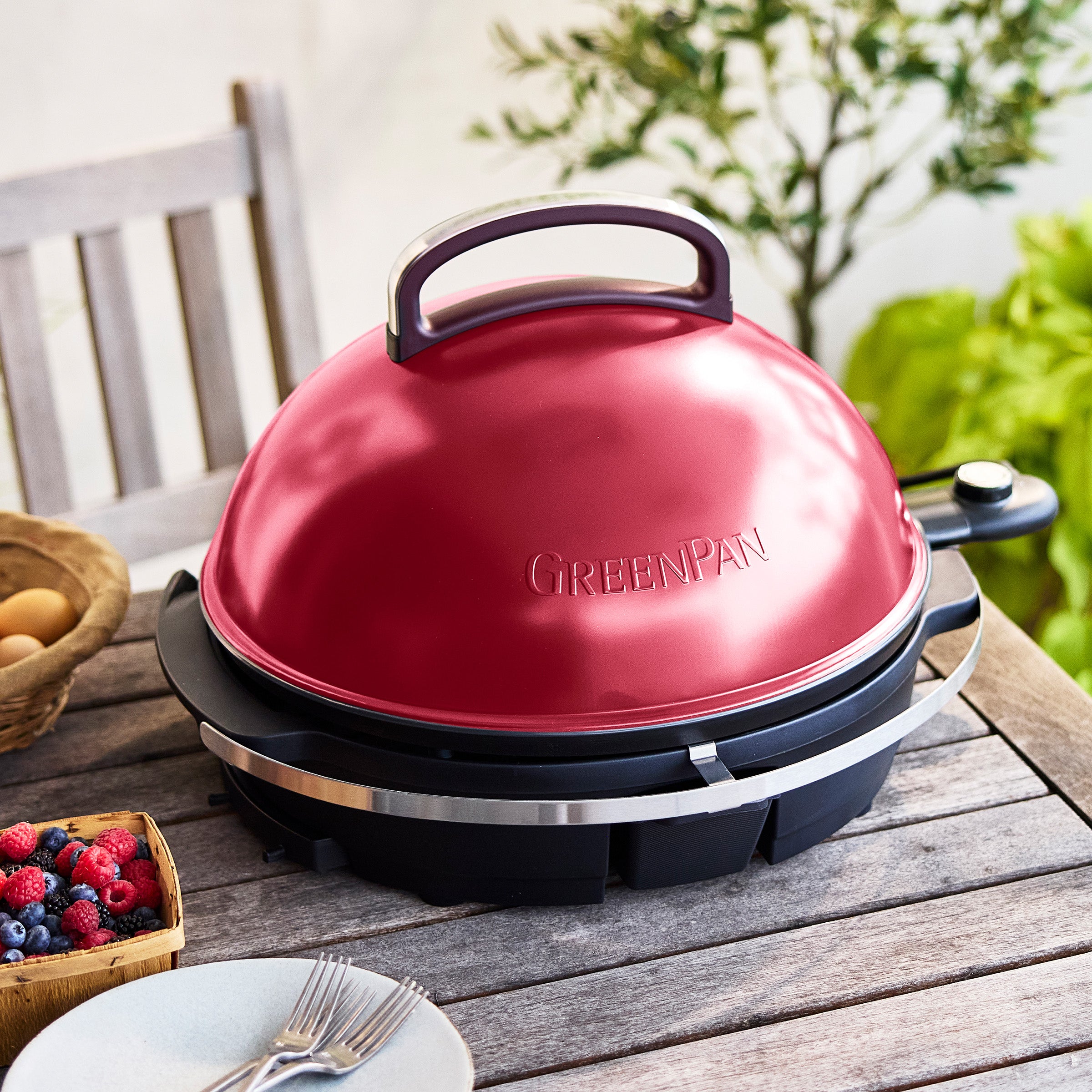 Red portable grill on a wooden table outdoors