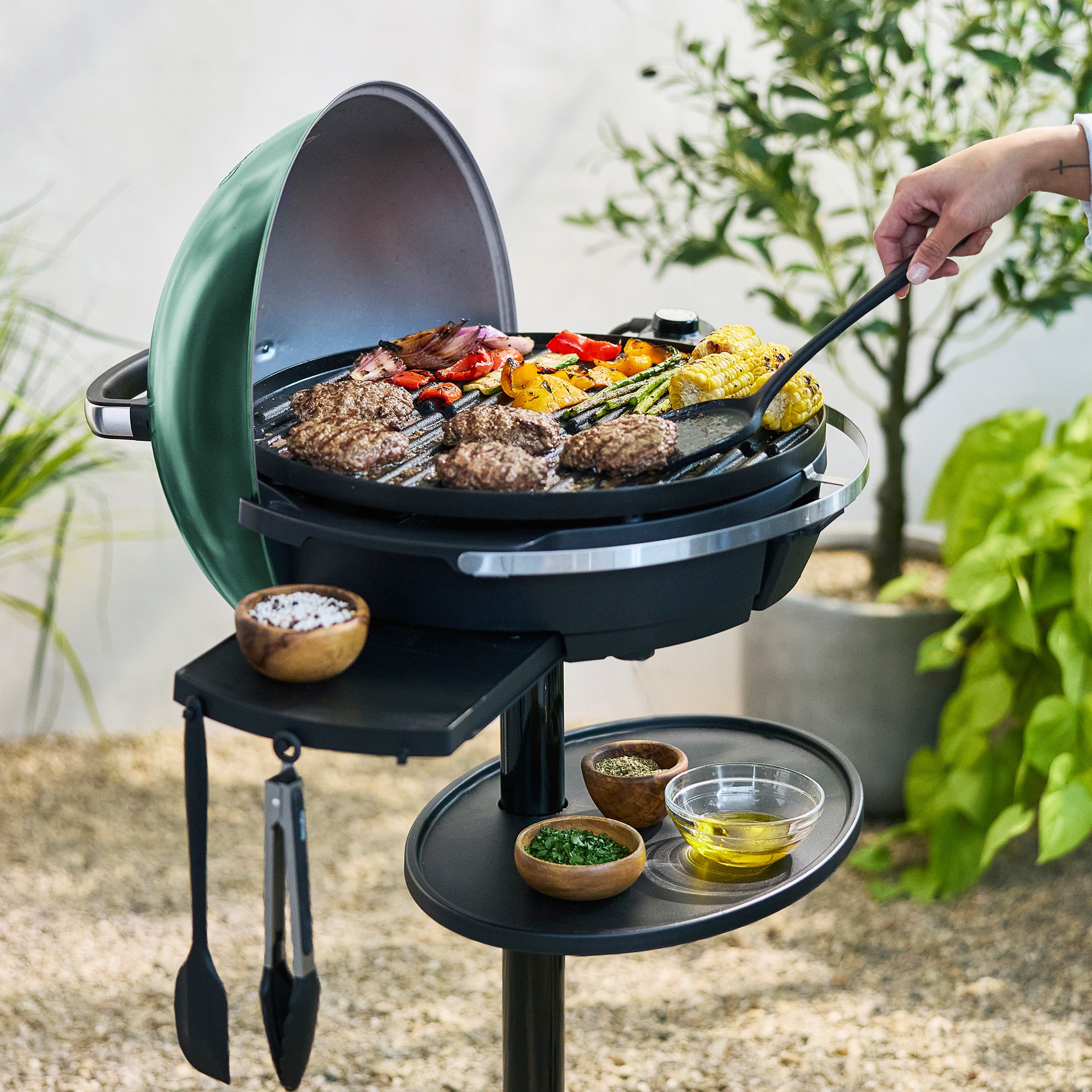 Green portable grill with food being cooked outdoors