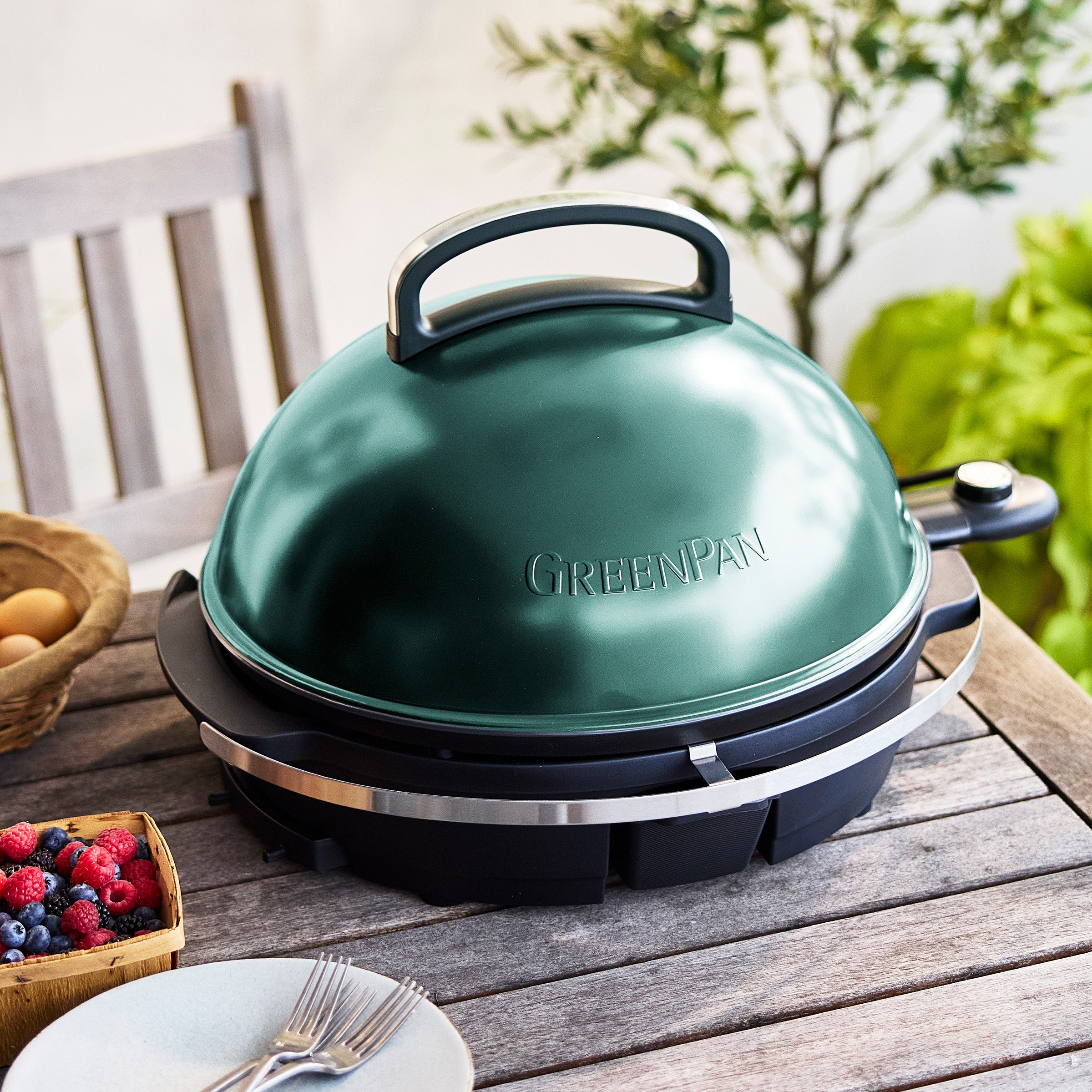 Green portable grill on a wooden table in an outdoor setting
