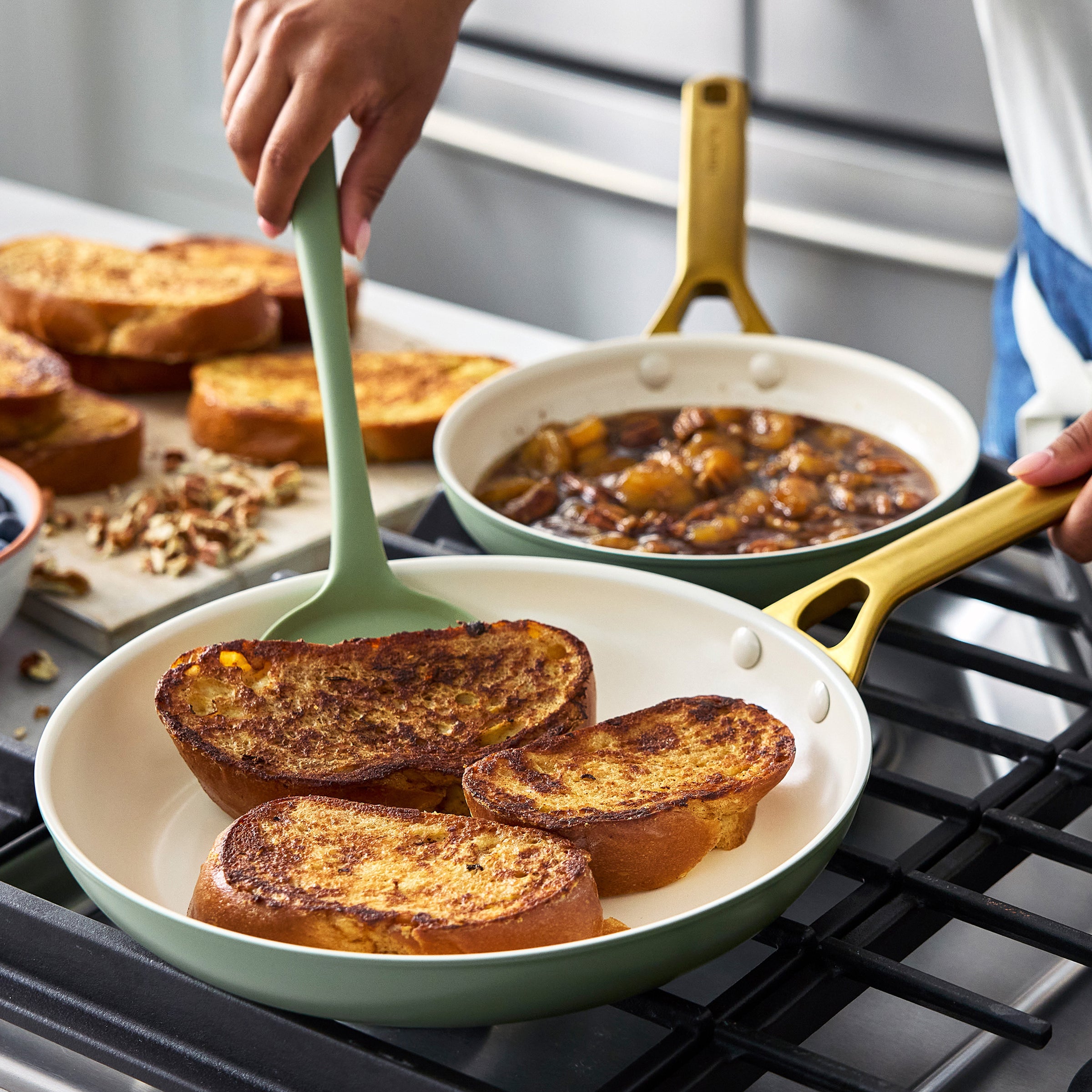 Person cooking French toast in a green frypan on a stove with a spatula