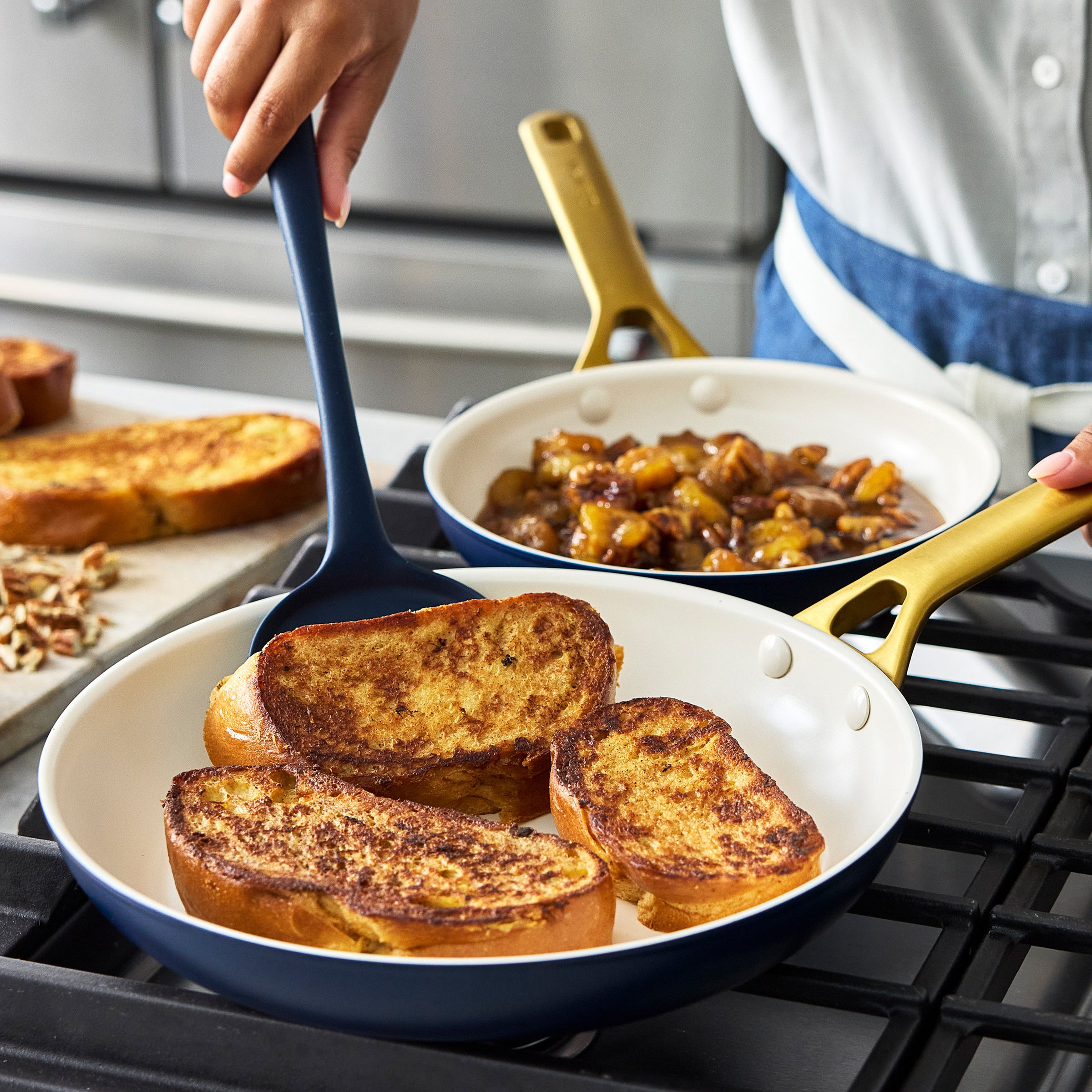 Person cooking French toast in dark blue frypans with a spatula