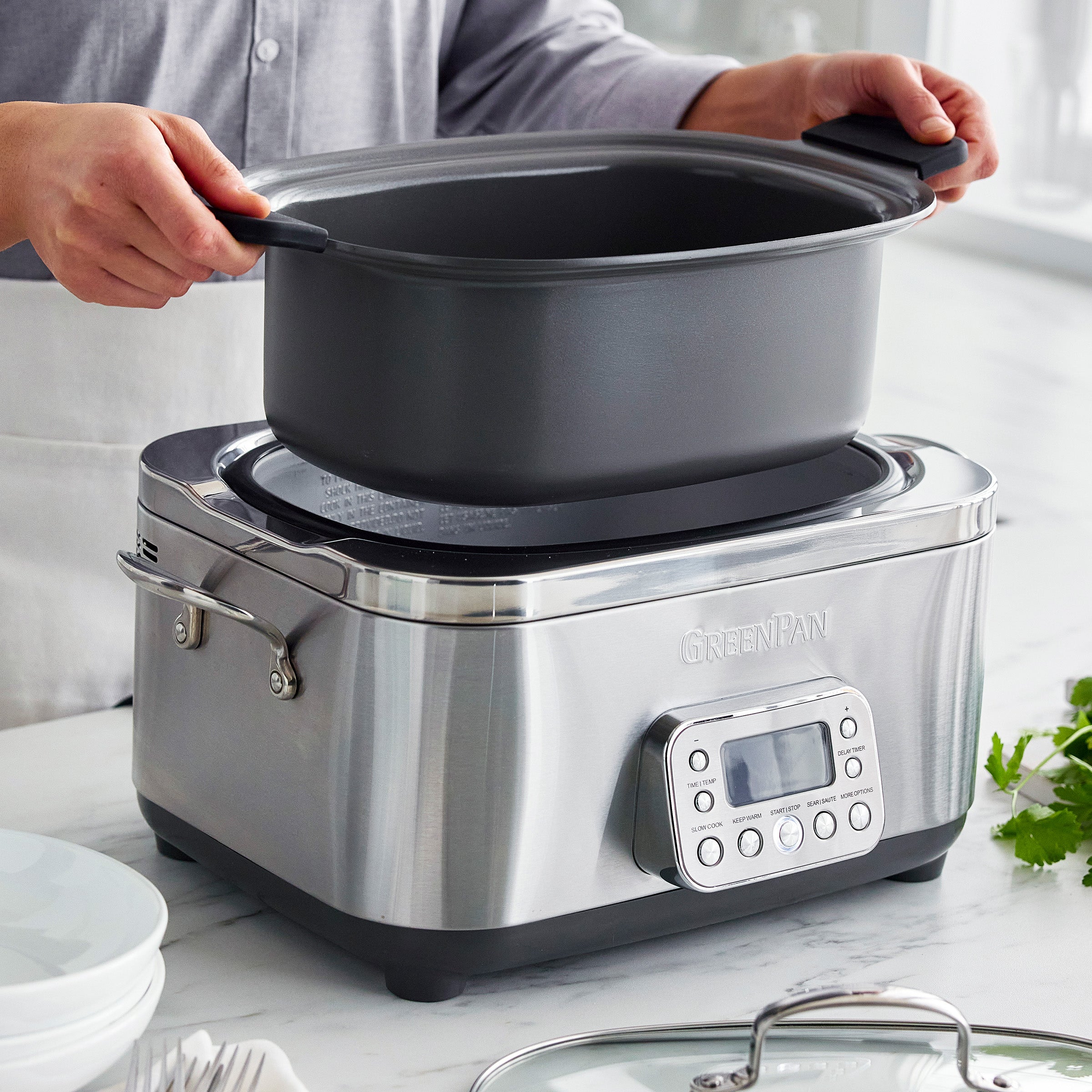 Person removing a pot from a slow cooker