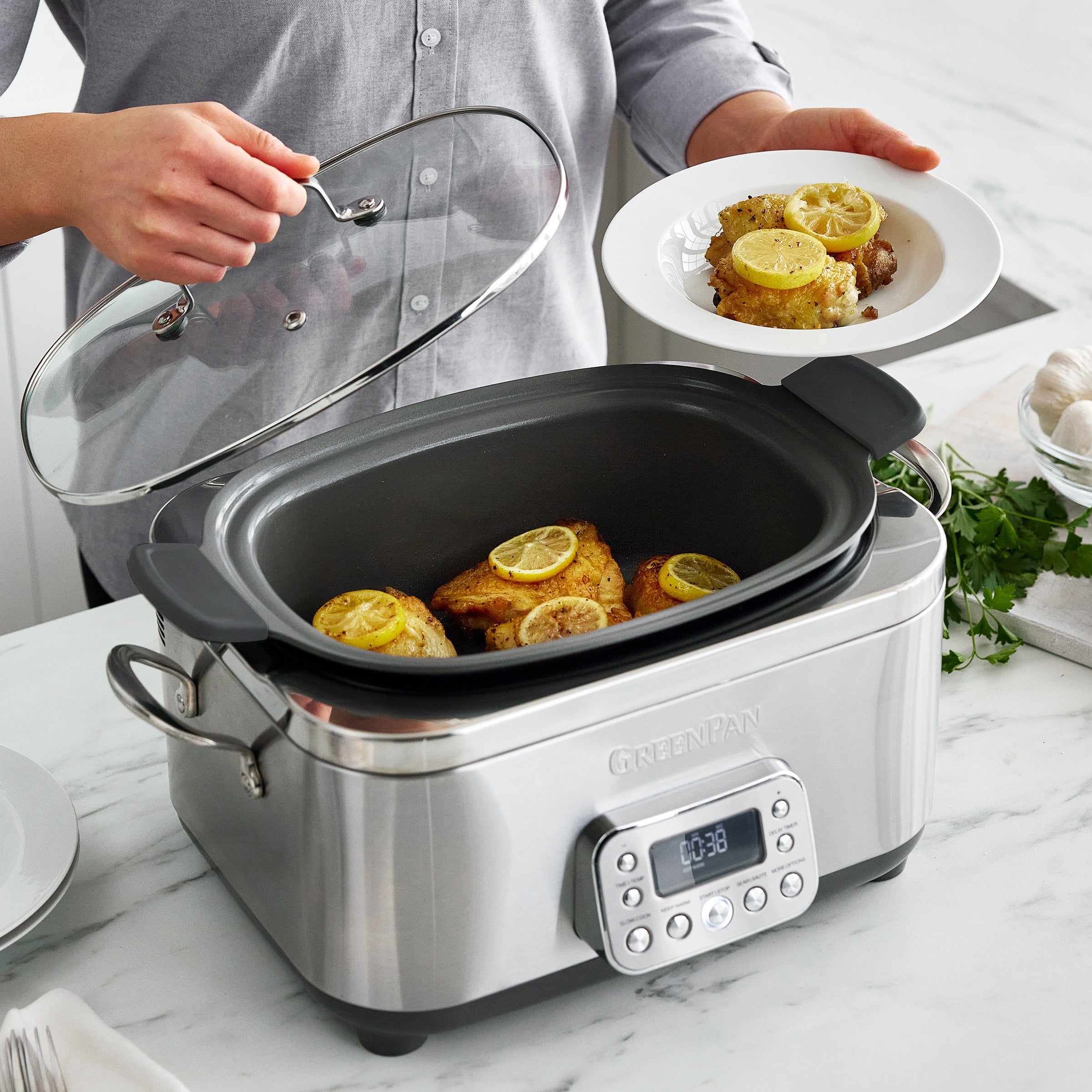Slow cooker with meat inside, person holding clear lid