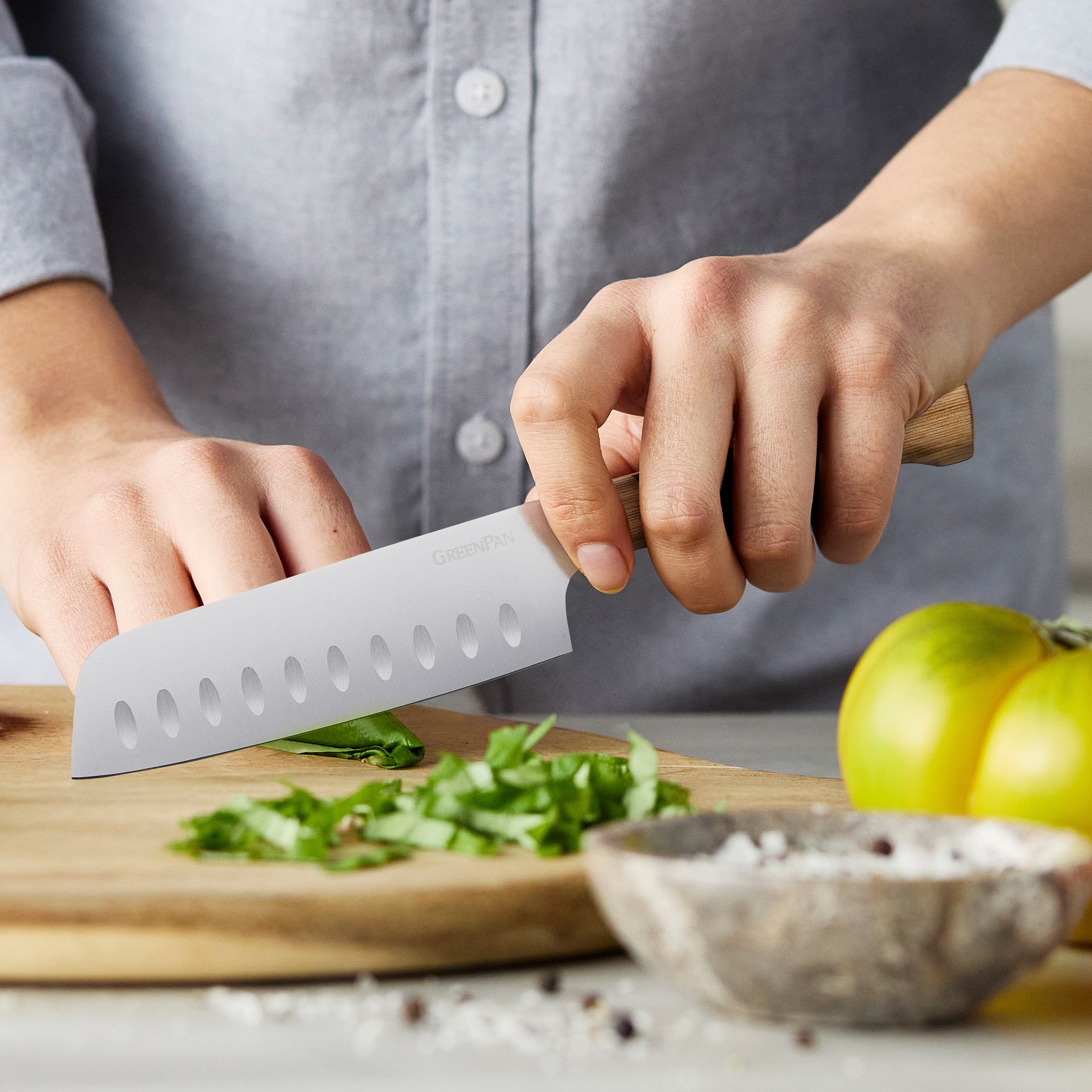 Person using a knife to chop greens on a wooden cutting board