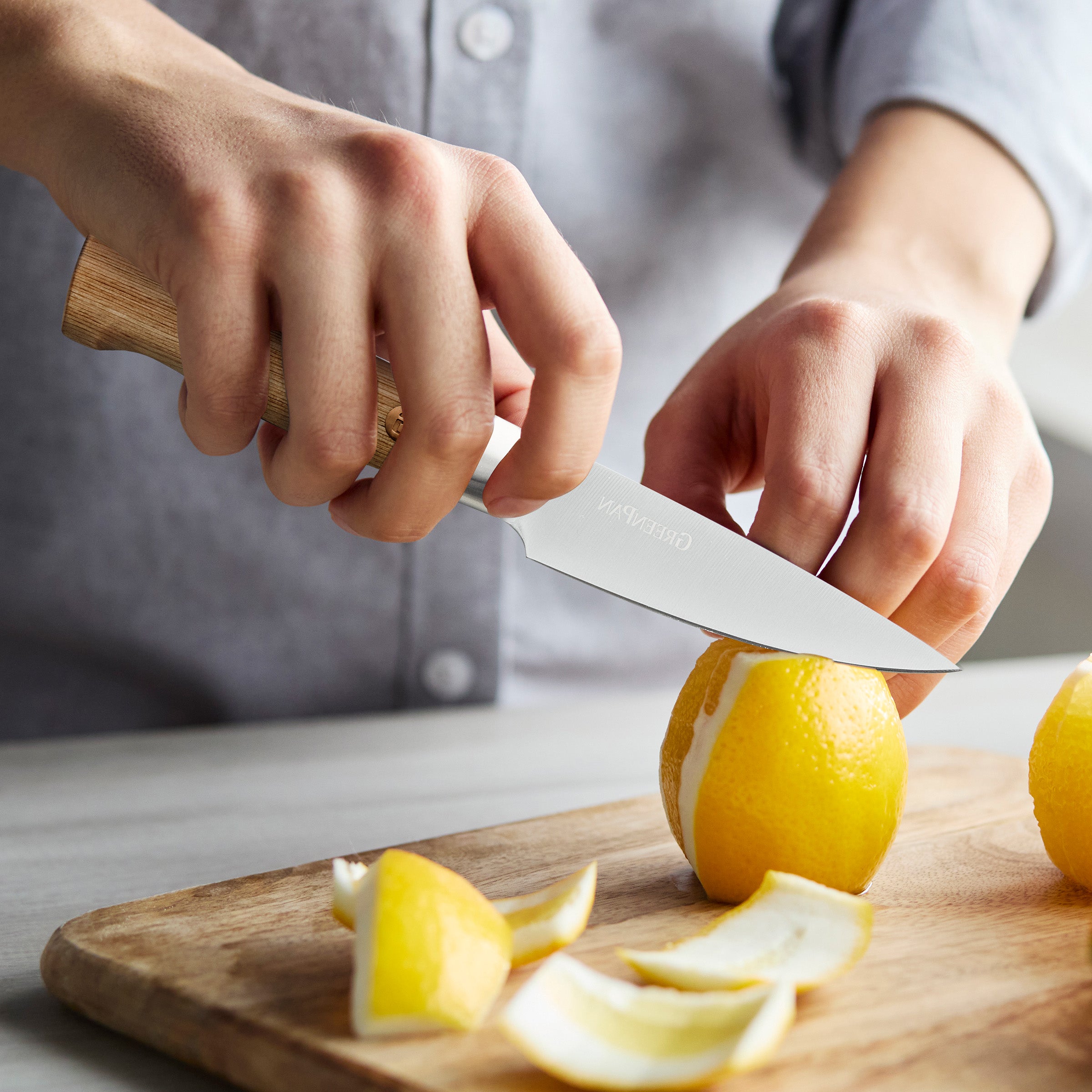 Person cutting lemons on a wooden cutting board with a knife