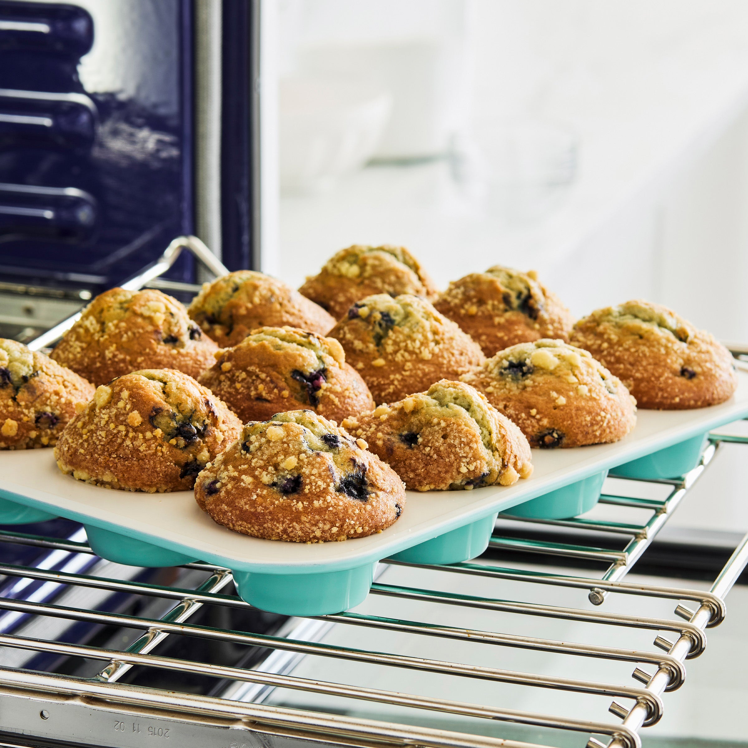 Muffins in a turquoise muffin pan sitting on an oven rack