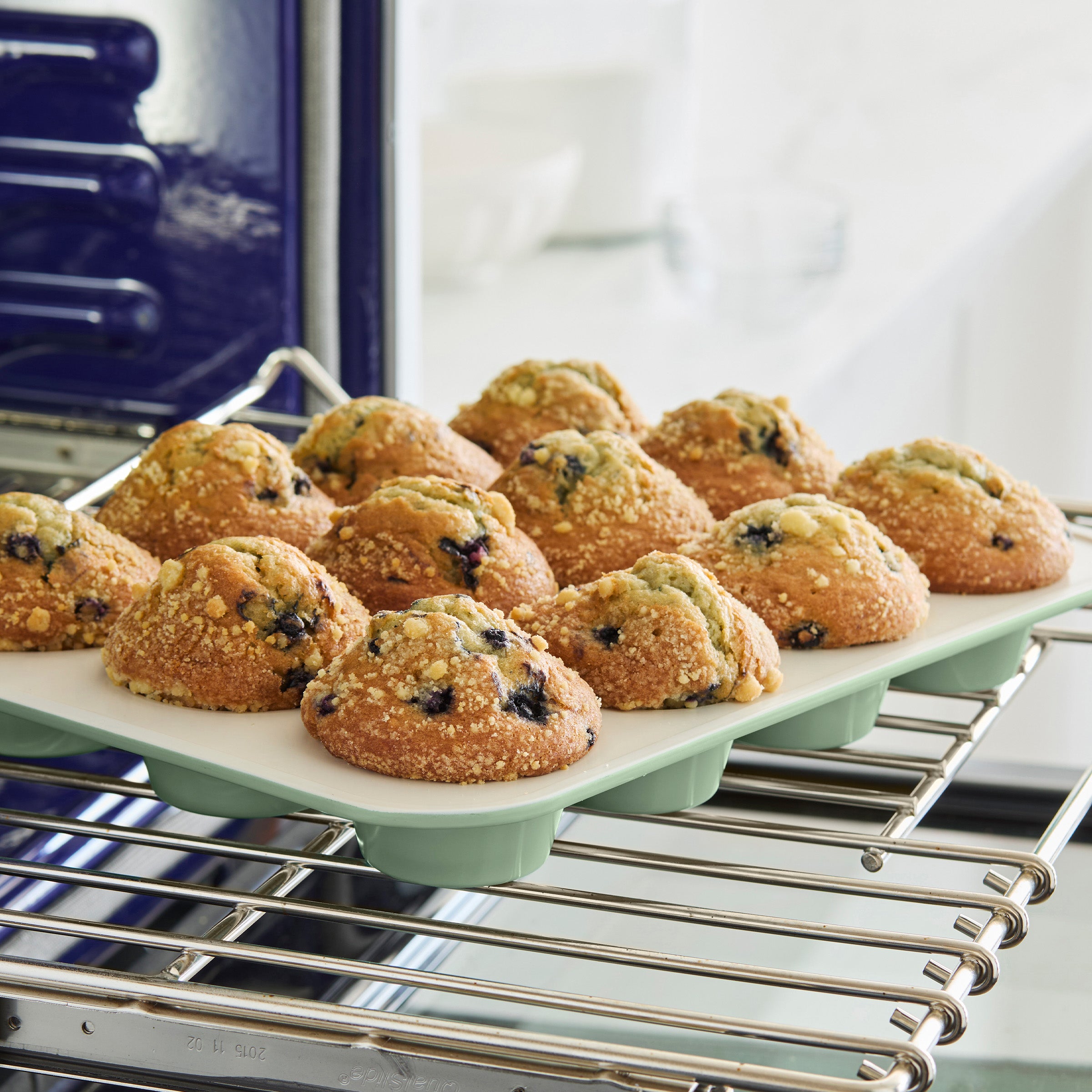 Muffins in a green muffin pan sitting on an oven rack