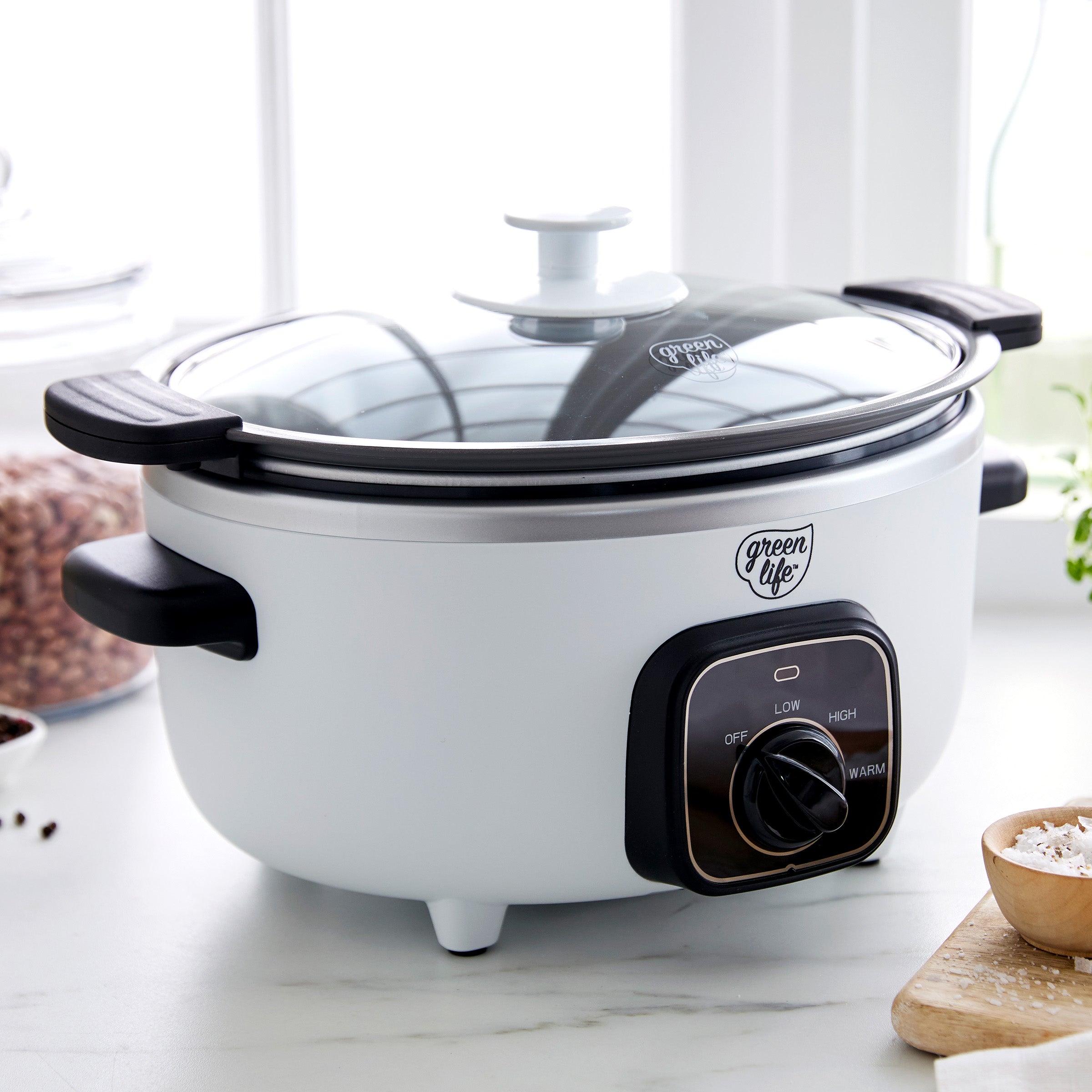 White slow cooker with black control panel on a marble countertop
