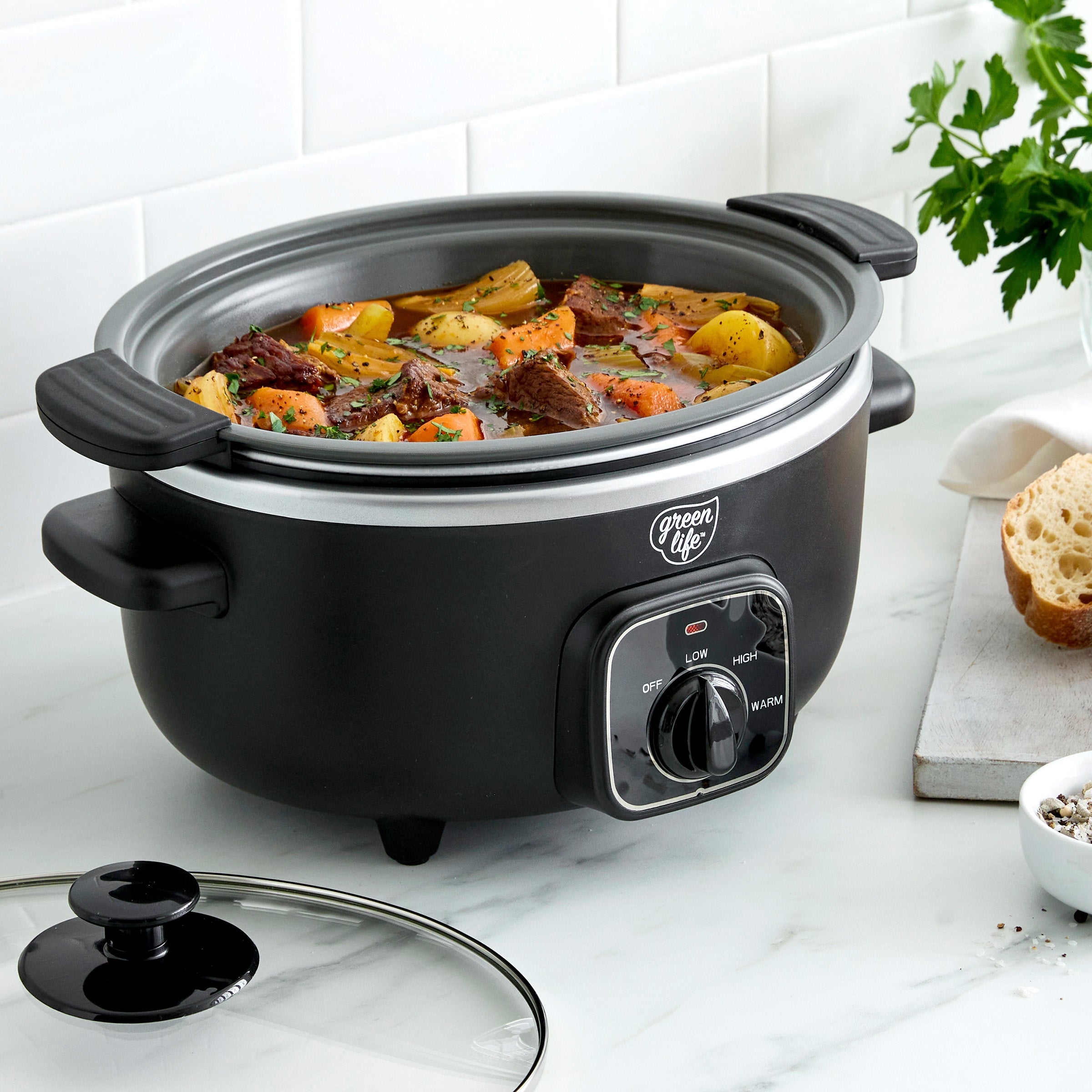 Black slow cooker with food inside on a white countertop
