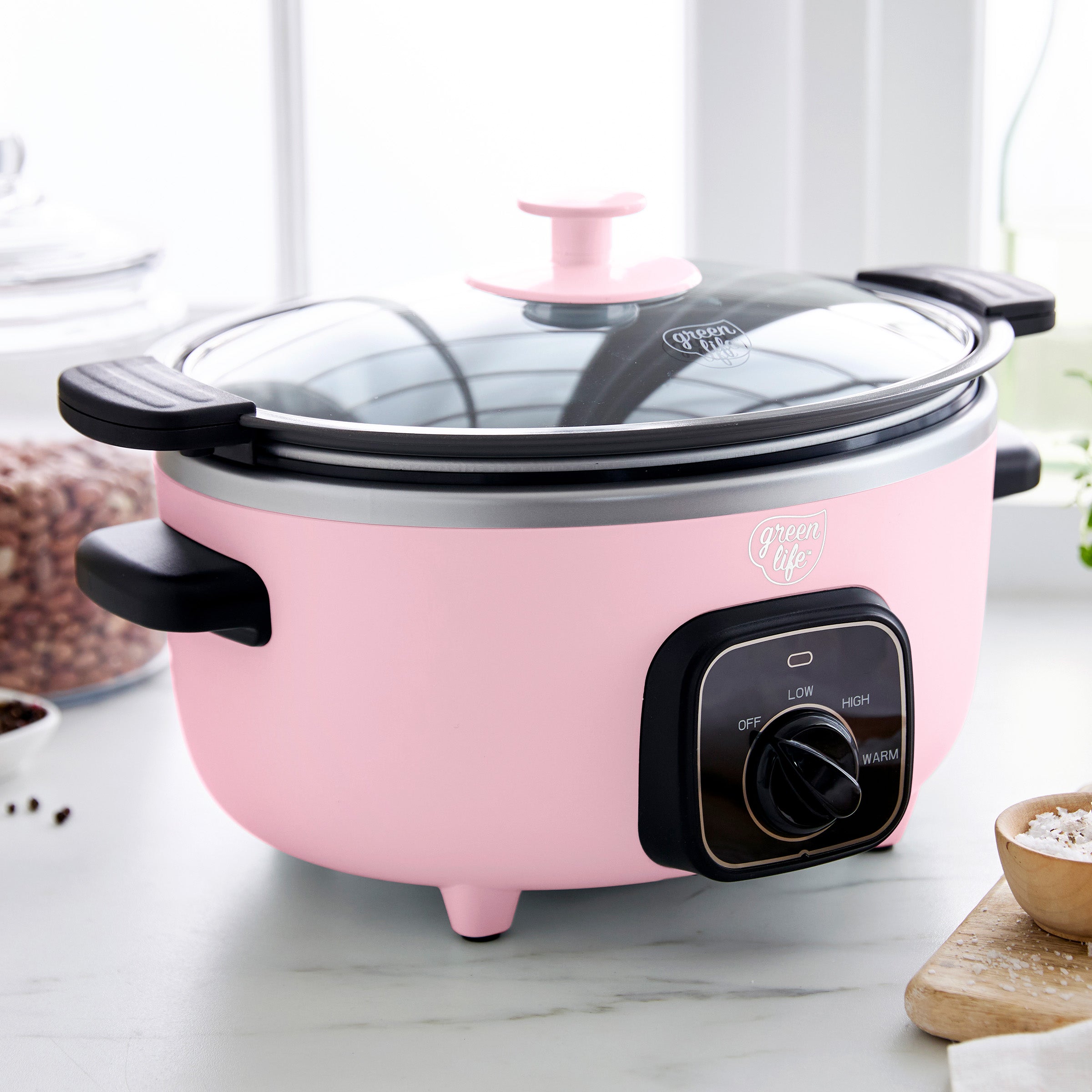 Pink slow cooker with black control panel on a marble countertop