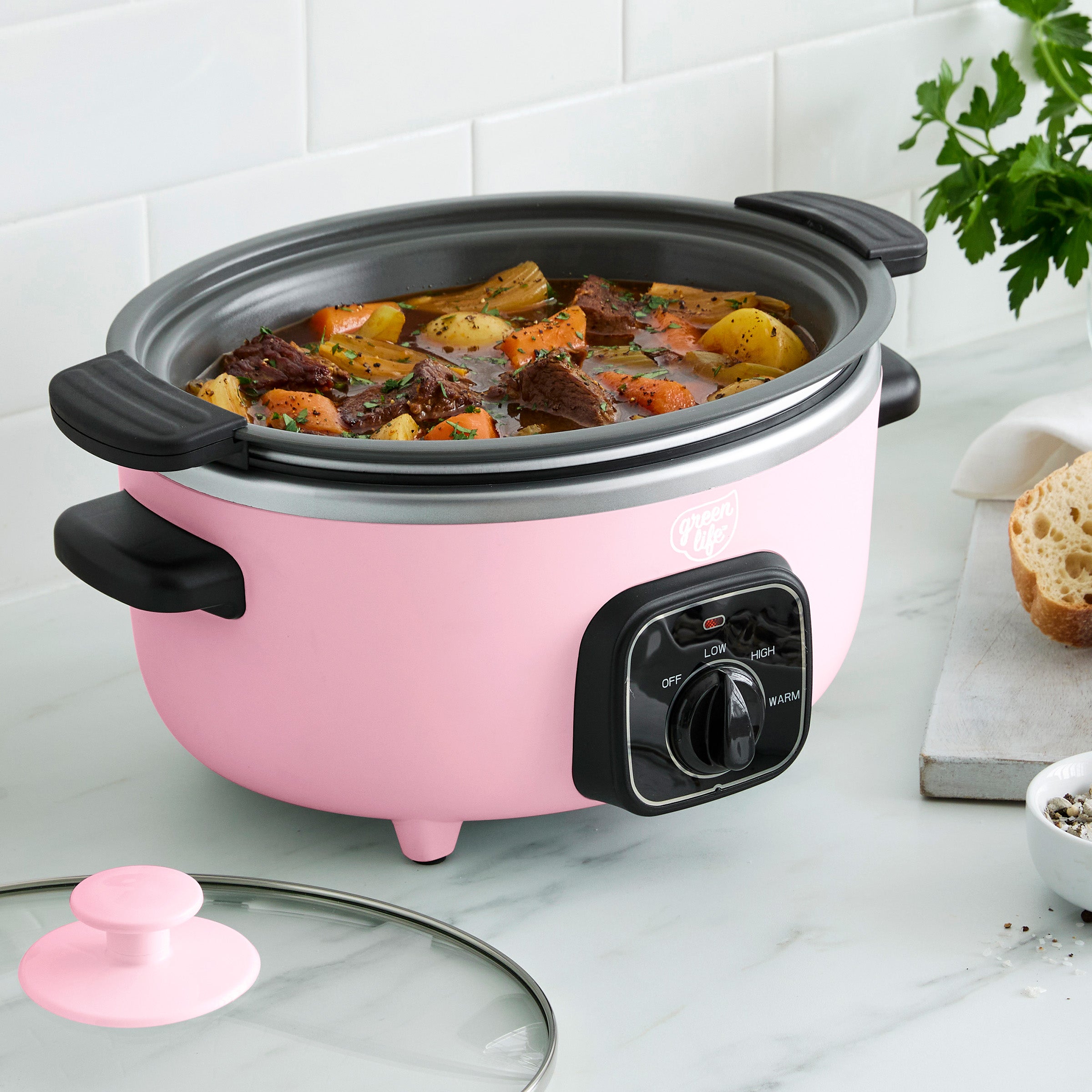 Pink slow cooker with beef stew on a kitchen counter