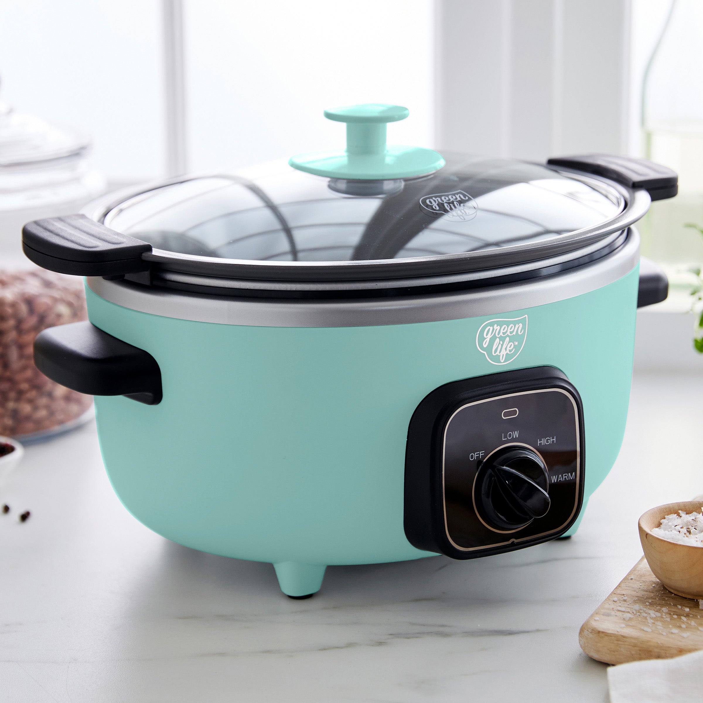 Turquoise electric rice cooker on a kitchen counter with a glass lid.