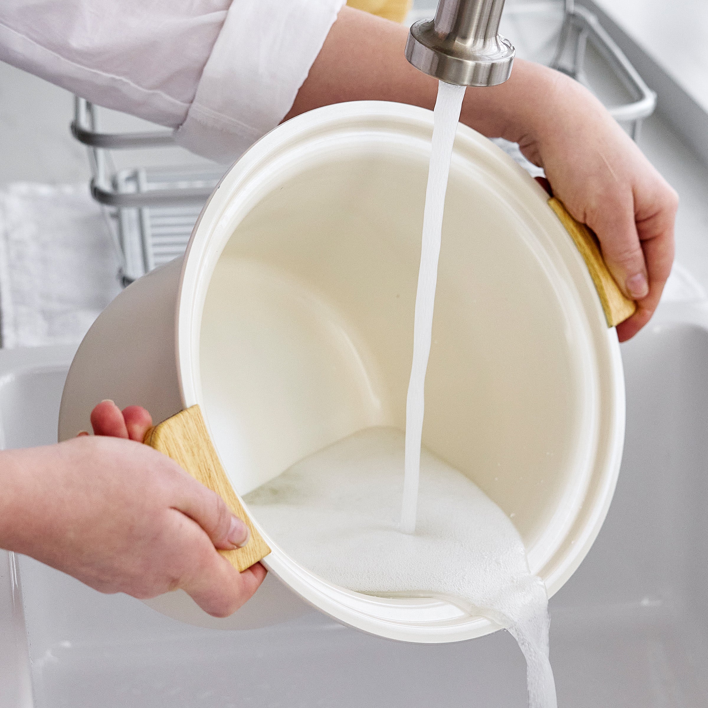 Person washing a pot with water from a faucet