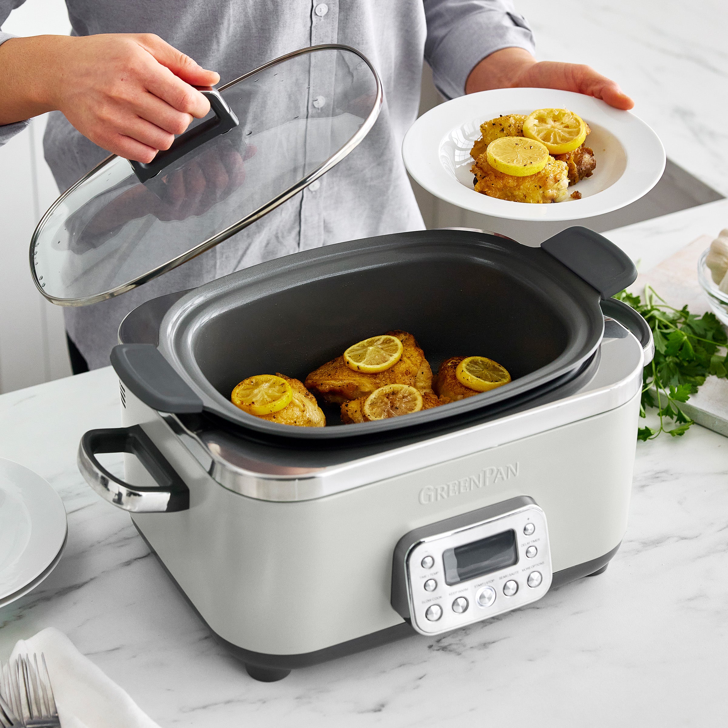 Slow cooker with meat inside, person holding clear lid